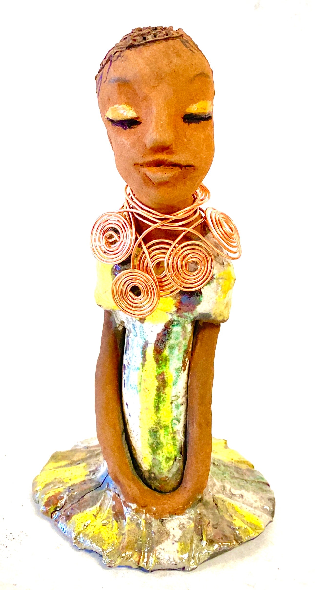 Meet Trisha! Trisha stands 9.5" x 5”x 5" and weighs 1.3 lbs. Trisha has a lovely glossy yellow green dress with a copper spiral necklace. Her hair is etched in clay. Her long arms rest at her side. Trisha is at a special low price. This makes her an excellent starter piece from the Herdew Collection!
