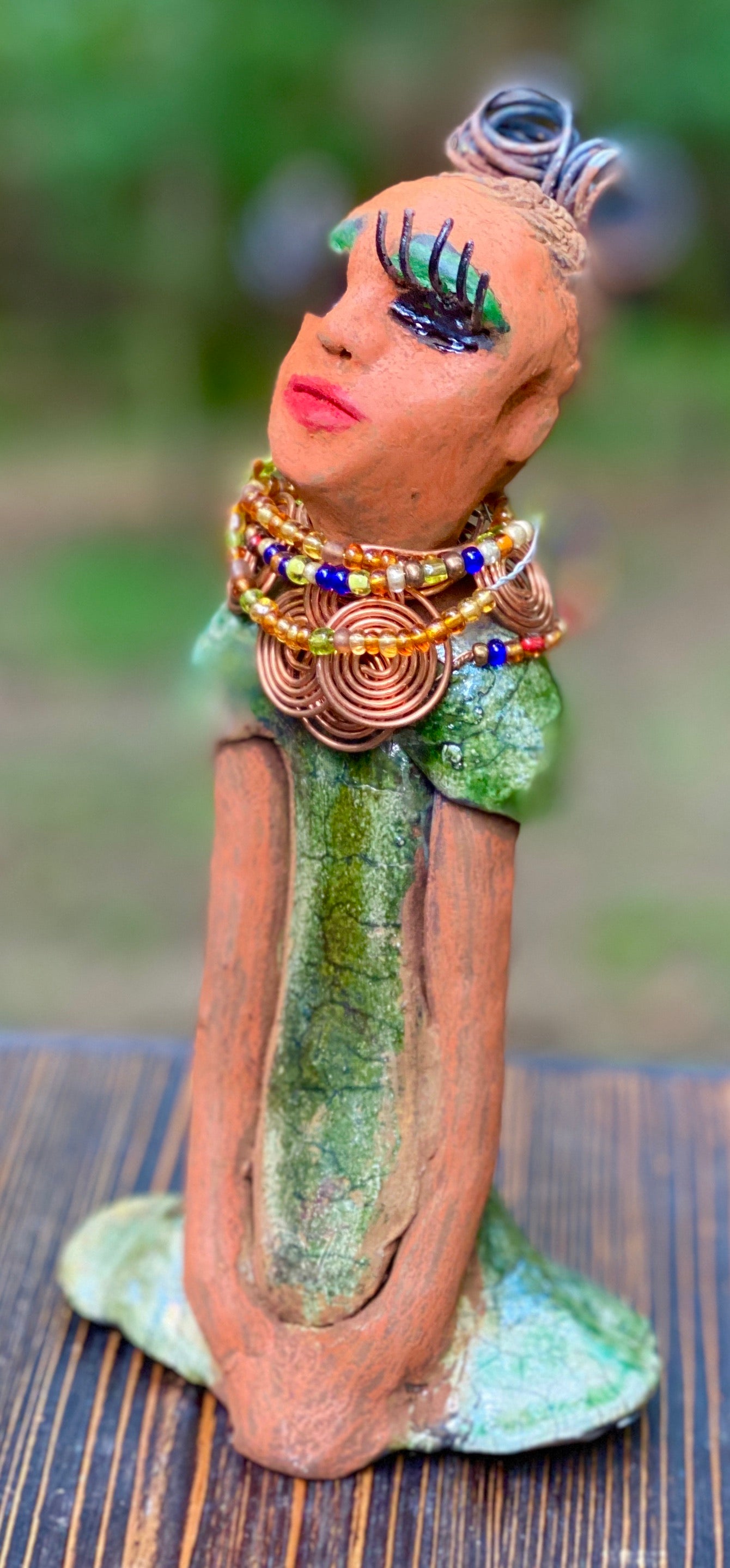 Kaleesia says yes to wire hair and yes to the Herdew tribe. Kaleesia stands 9” x 5" x 2.5" and weighs 1.05 lbs. She has a lovely beige brown complexion with short etched braided clay hair. Kaleesia long loving arms rest beside her multicolored copper green dress. Kaleesia is a sophisticated lady that will grace your home.