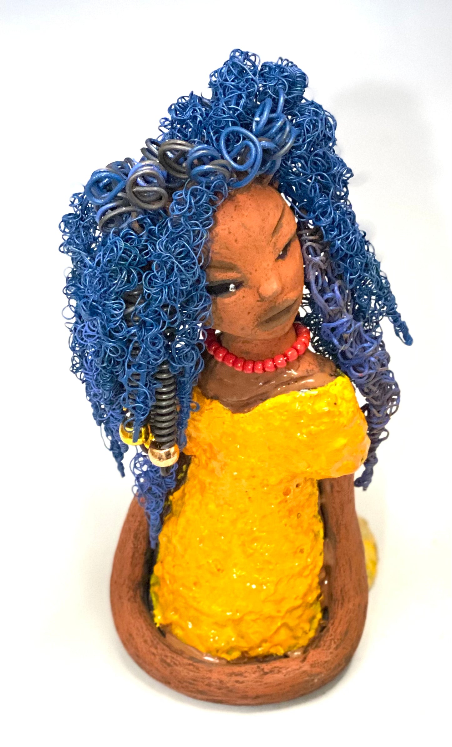 Makeba stands 8" x 5" x 5" and weighs 1.4 lbs. She has a lovely honey brown complexion with cocoa red lips. She has long twisted blue wire locs hairstyle waist down! Makeba has a sunset yellow red glazed dress. She has over 75 feet of 16 and 24 gauge blue wire for hair. It took over 5 hours just to do her hair! With eyes wide opened and a subdue look, Makeba has hope of finding a new home.