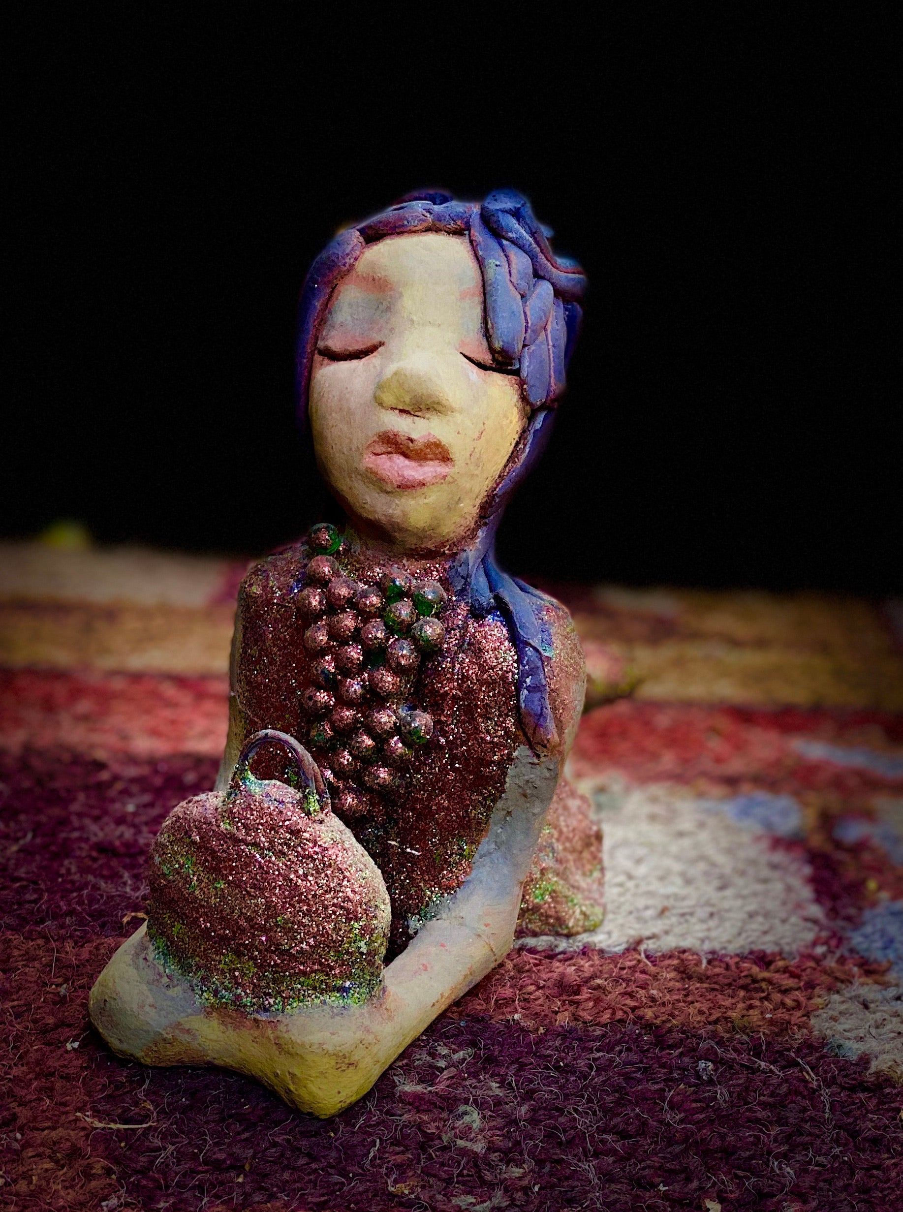 Lacey is going places but she's not leaving her bag! Lacey stands 6" x 3" x 7.5" and weighs 1.08 lbs. She has a lovely beige olive green complexions with ruby red lips. Her hair is made of coiled clay. Lacey is holding her handbag which matches her copper glittered dress.