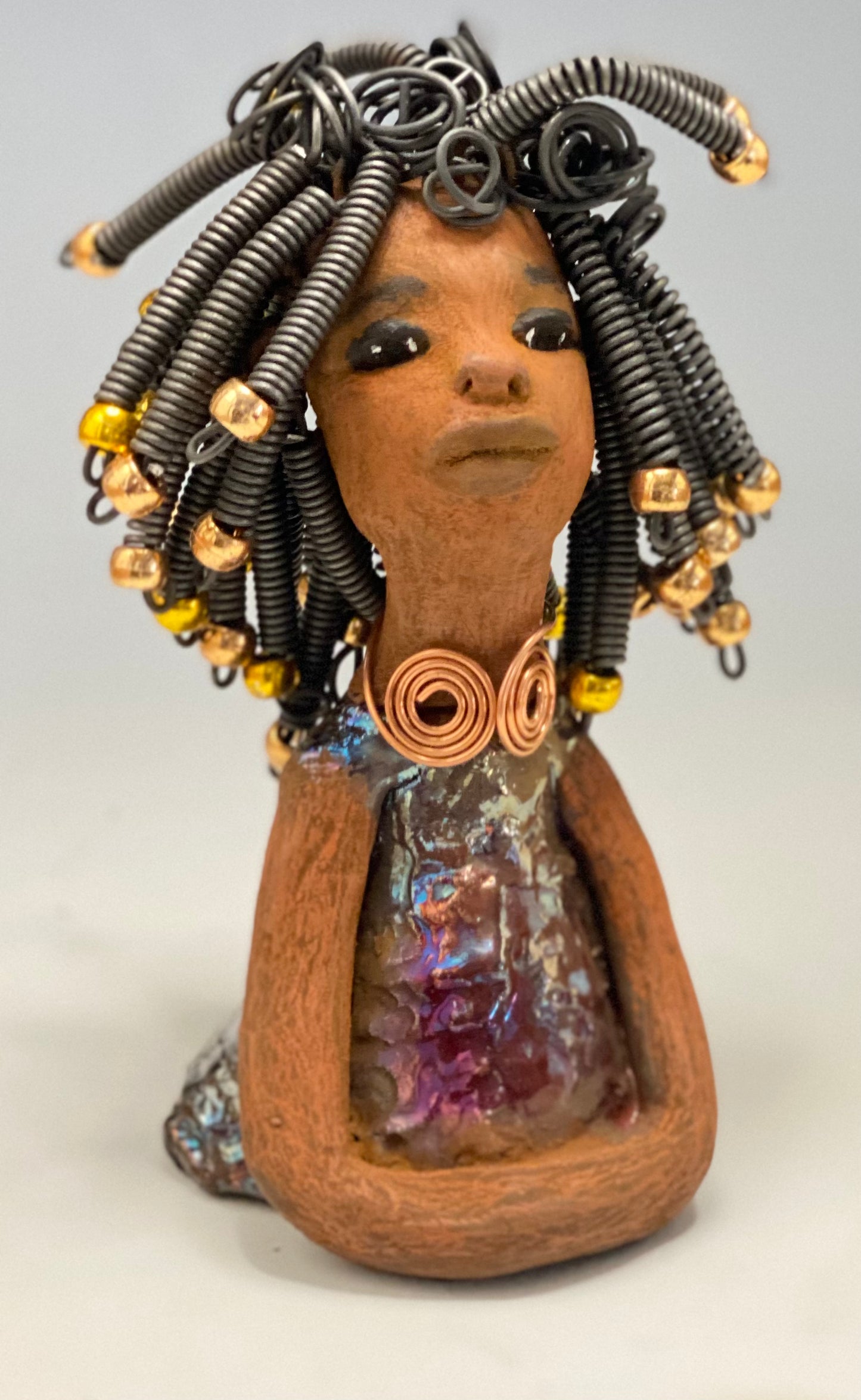Meet Alexus Alexus stands 7.5" x 4" x 4" and weighs 1.05 lbs. She wears a lovely glossy metallic gold dress adorn by a spiral copper necklace. Alexus has over15 feet of coiled wire hair with gold beads.. Alexus appears to sit in a yoga pose. Her long arms rest at her side. Alexus is a great starter piece from the Herdew Collection!