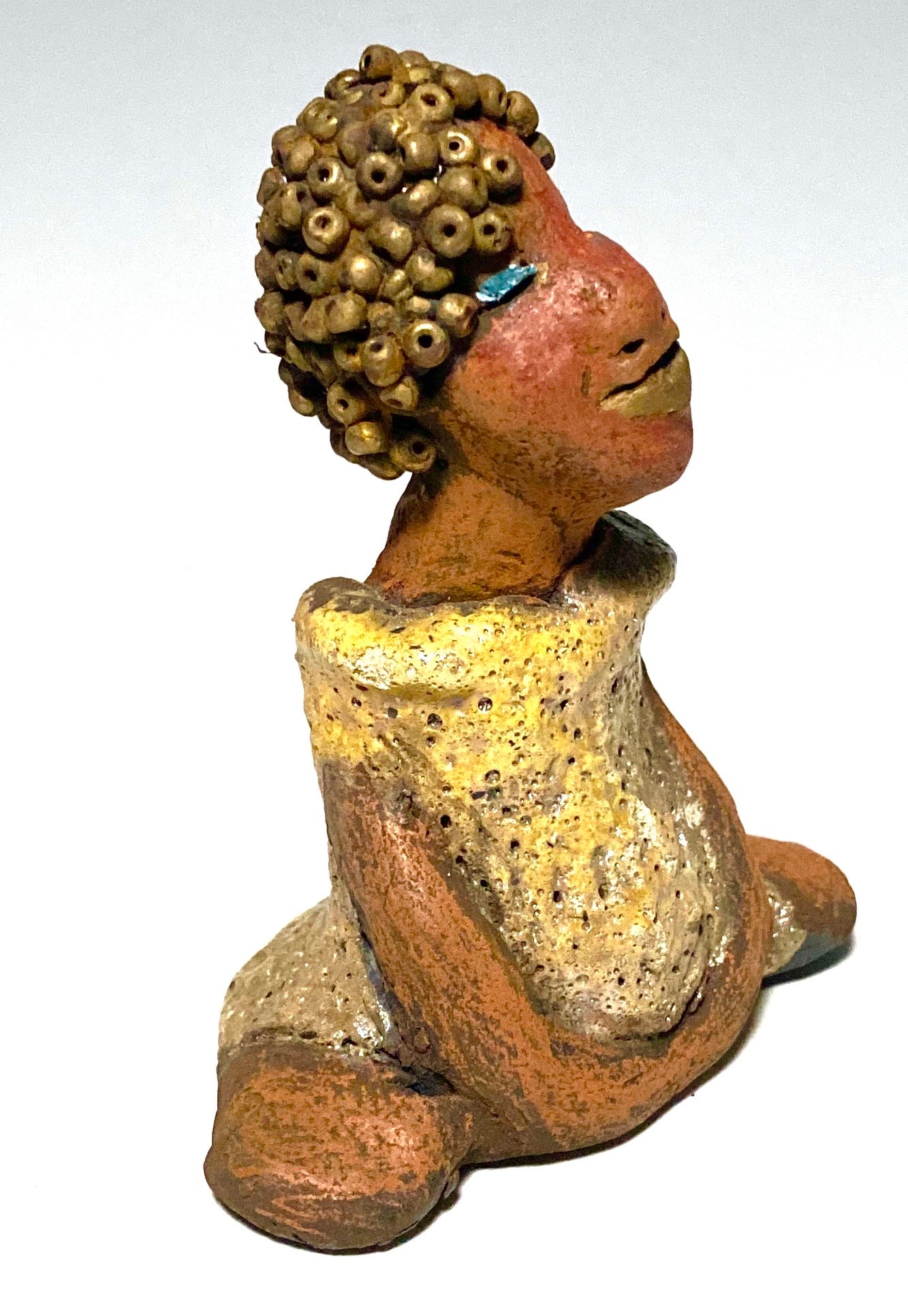 Meet Little Marissa! Marissa stands 4.5" x 4" x 2.5" and weighs 6.7 ozs. Marissa has a lovely glossy gold dress. She gold beaded hair. Marissa appears to sit in a yoga pose. Her long arms rest at her side. Marissa is a great starter piece from the Herdew Collection!