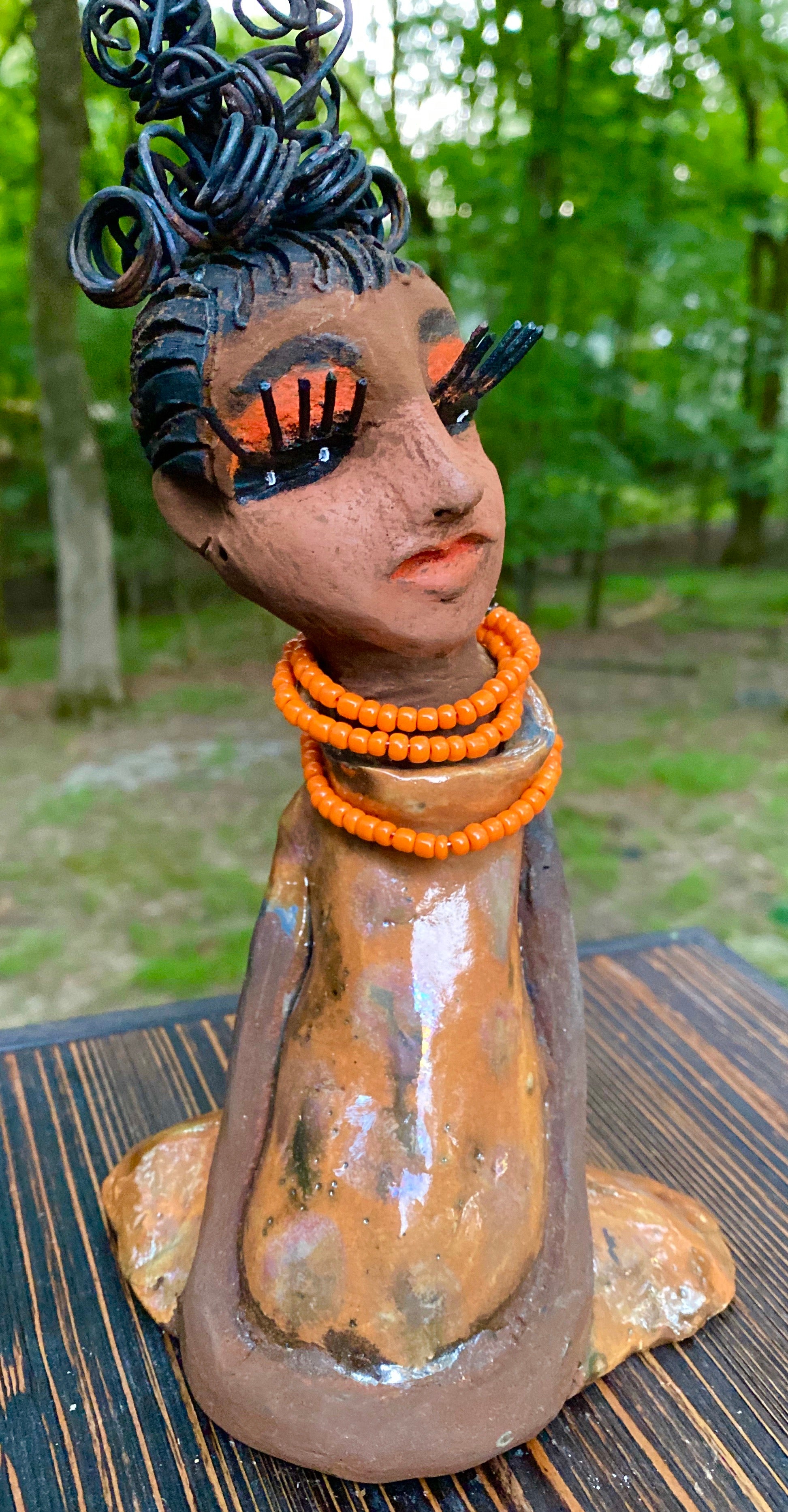 Meet Abimbola ! Abimbola stands 7' x 4"x 2" and weighs 1.3 lb. She has bright eyes and a nice honey brown complexion Abimbola  has over 5 feet of 16 gauge wire hair wrapped in a bun. Her long trademark arms rest at her side. Abimbola dress is a loving glossy orange mix with copper flashes. Abimbola is waiting for you to invite her into your home!