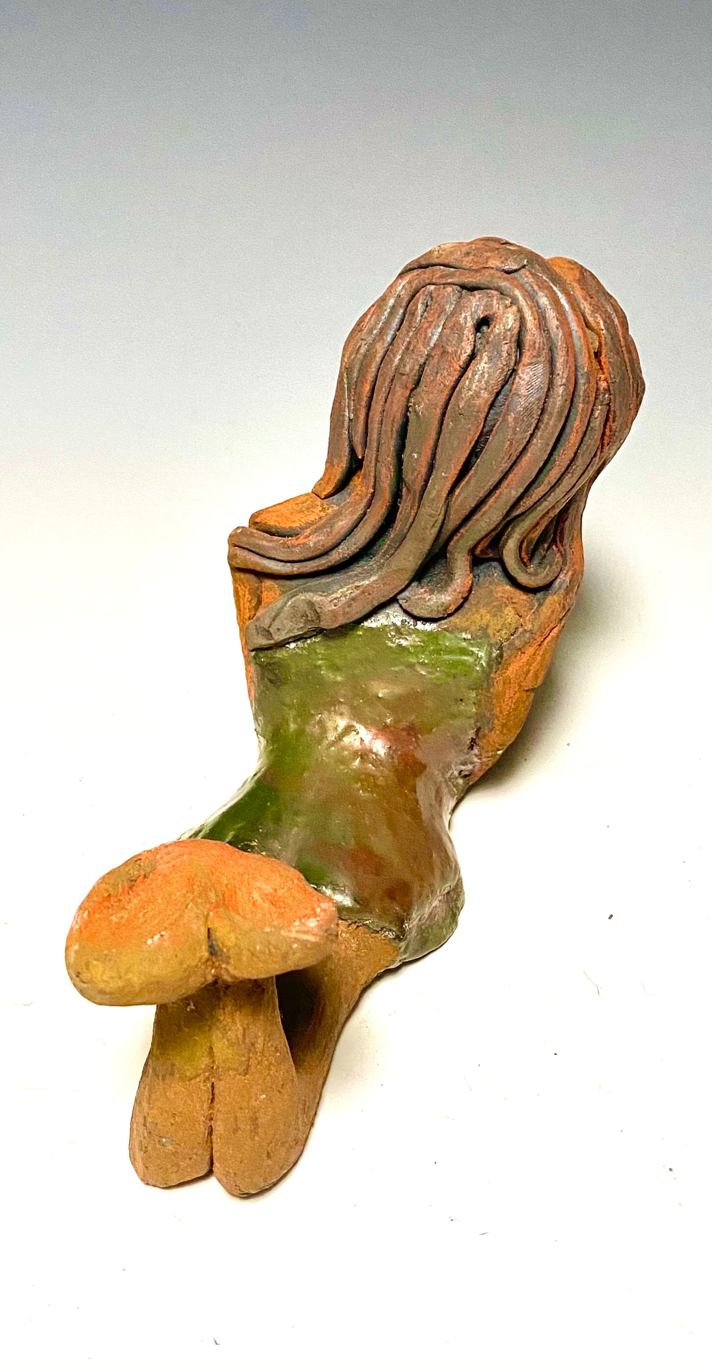 Marie waits patiently! Marie stands 6" x 3.5" x 7.5" and weighs 1.11 lbs. Marie has a lovely honey brown complexion with ruby red lips.. Her long loving arms are underneath her face as she ponders. Marie dress is a copper glazed and she has hair made of clay. Marie is bright eyed and ready to be placed in a good home.