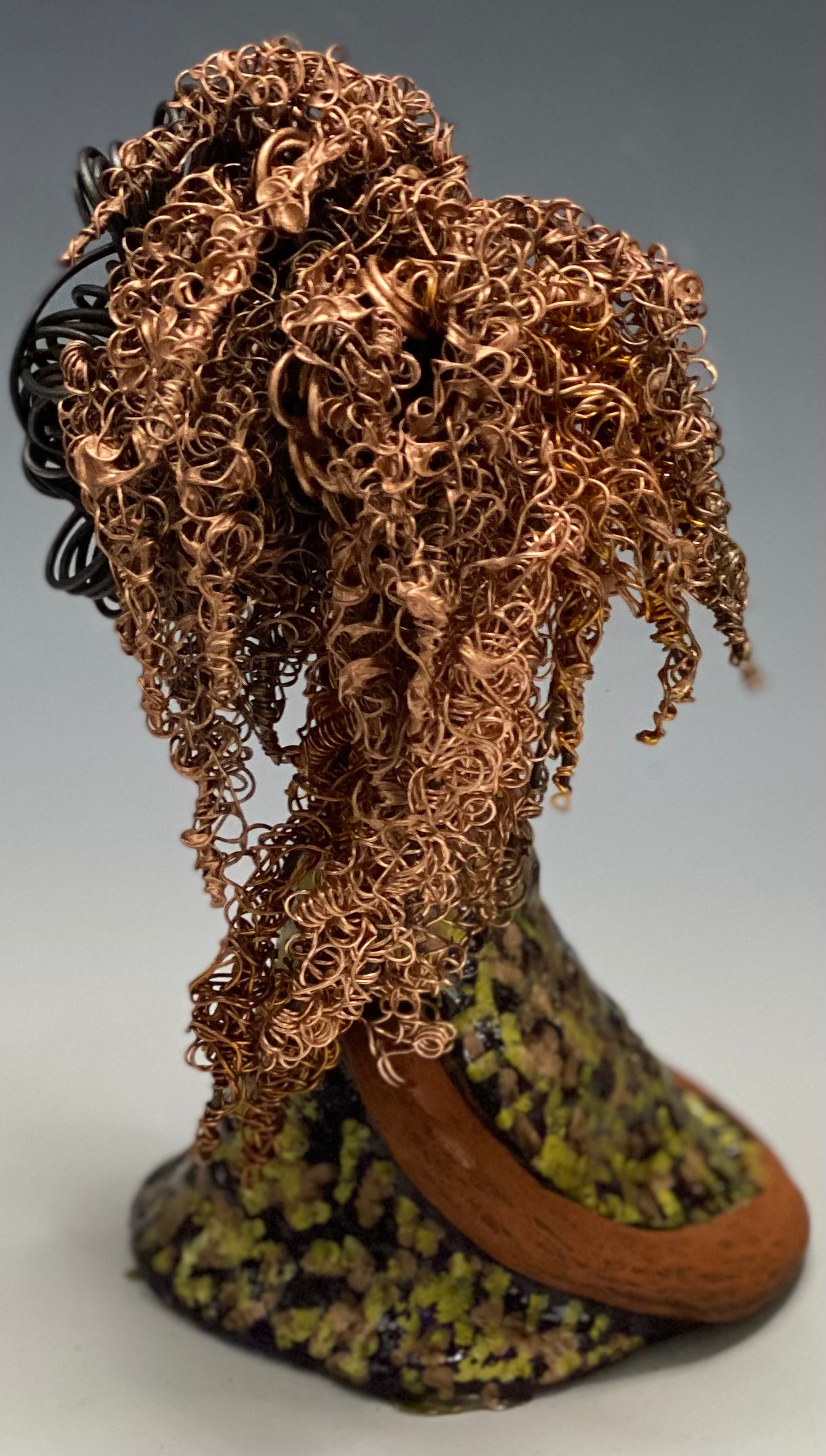 Meet Kalifa, an elegant figurine weighing 1.11 lbs and measuring 8" x 5" x 5.5". Her glossy spotted metallic copper glazed dress and long twisted wire locs are expertly crafted. With her honey brown complexion and red lips, she is sure to capture the attention of your guests. Her daring two-tone copper hair, which took 6 hours to create, adds to her beauty.