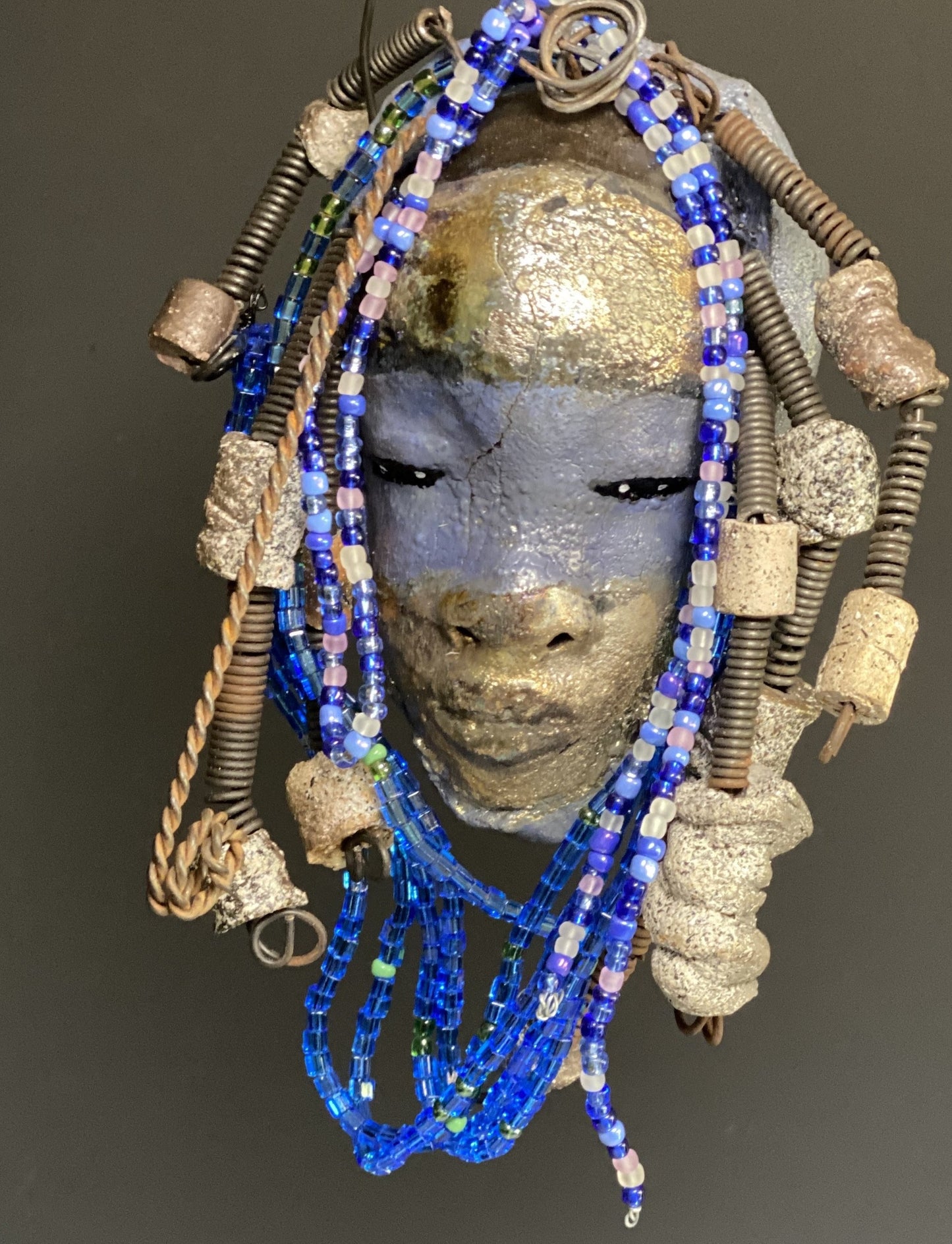 Meet Randi! I started making art soon after seeing authentic African artwork at the Smithsonian Museum of African Art. I was in total awe. Randi was inspired by my visit there. Randi has a two tone complexion of golden silver and blue. She is 8" x 6" and weighs 14 ozs. Randi has over 10 raku beads. She has over 200 of multi shade of blue and white mini beads. Randi has over 10 feet of coiled copper and 16 gauge wire hair.