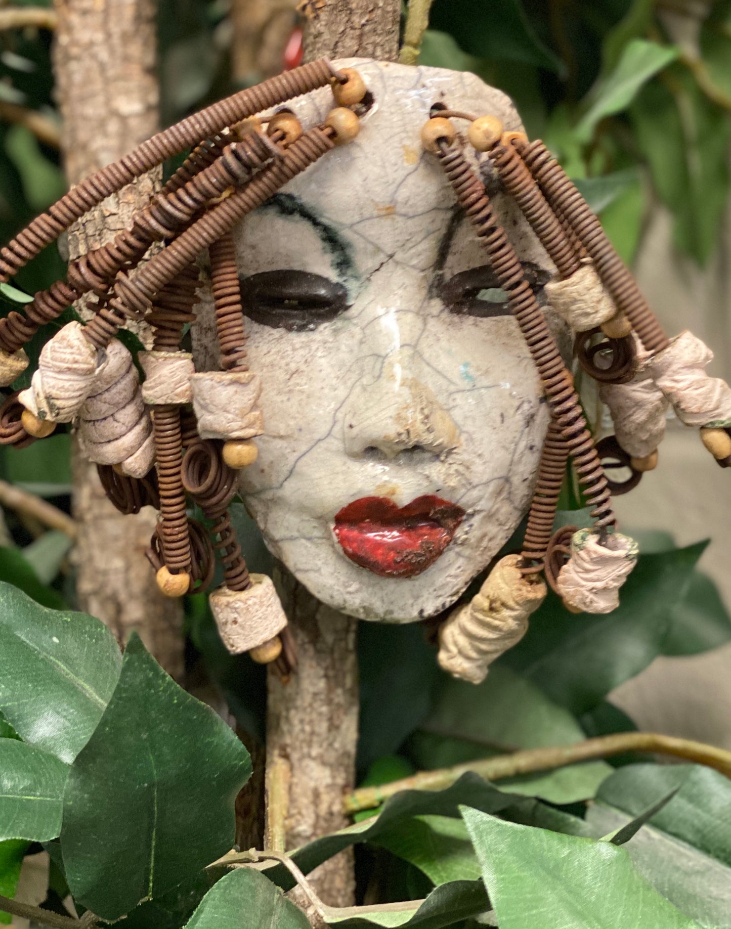 Larandra has a white crackle complexion. She is 6" x 5" and weighs 1.6 lbs. Larandra has over 20 feet of coiled 16 gauge wire hair and several wooden and white raku beads.