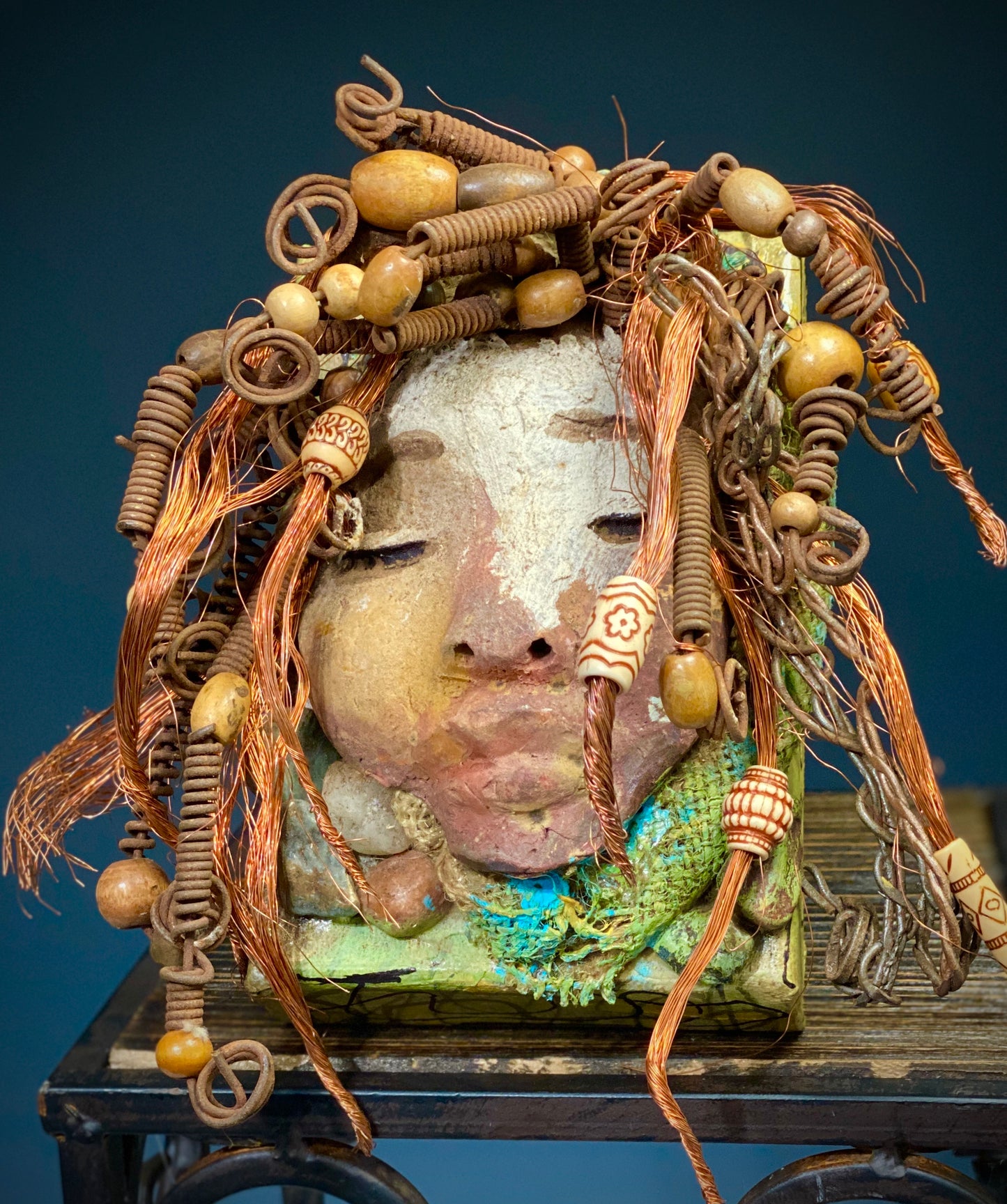 I started making art soon after seeing authentic African artwork at the Smithsonian Museum of African Art. I was in total awe. Lulu was inspired by my visit there. Lulu is uniquely mounted on a painted 6"x 4"x 2" canvas. It weighs 1.15 lbs. Her face has a two tone off white and earthy crackle glaze. Lulu has hand coiled wire, white and multi color beads, textured earthy cloth..