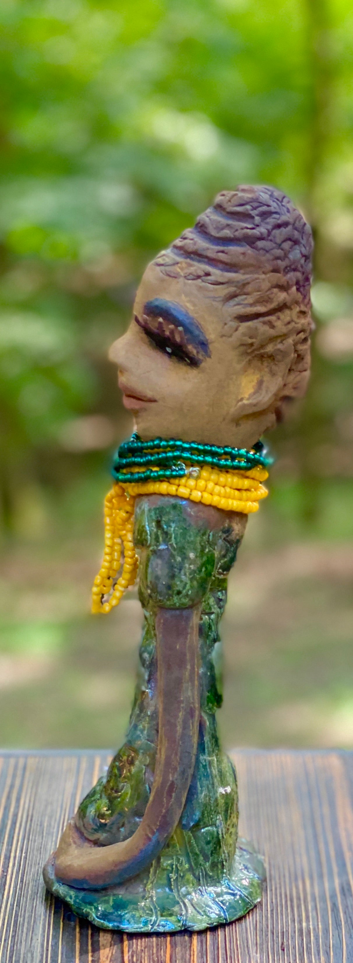 Meet Jazmyne! Jazmyne stands 11" x 4" x 4" and weighs 2.5 lbs. She has a lovely honey brown complexion with reddish brown lips. She has a braided hairstyle. Jazmyne has a colorful metallic green antique copper glazed dress. She wears a bright yellow beaded necklace. With long lashes and eyes wide opened, Jazmyne has hopes of finding a new home. Jazmyne will attract and spark conversation with guest in your home!