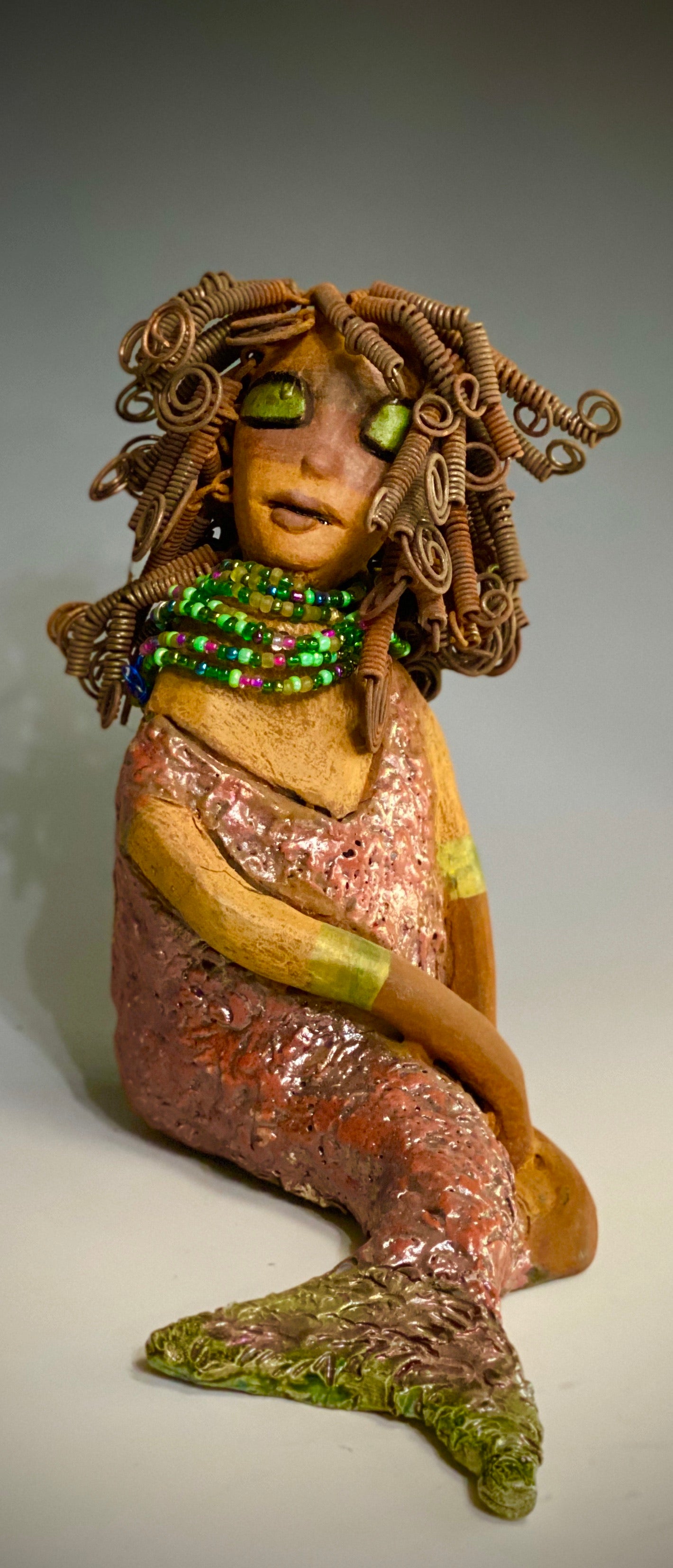 "Honestly, I can not explain where this desire to make mermaids come from. When I created my first raku fired mermaid, I was amazed at how well my homemade metallic copper green glaze worked with the mermaid's body suit. It was a good match with the honey brown complexion I use with most of my sculptures". Compare Meranda with Melody the mermaid.