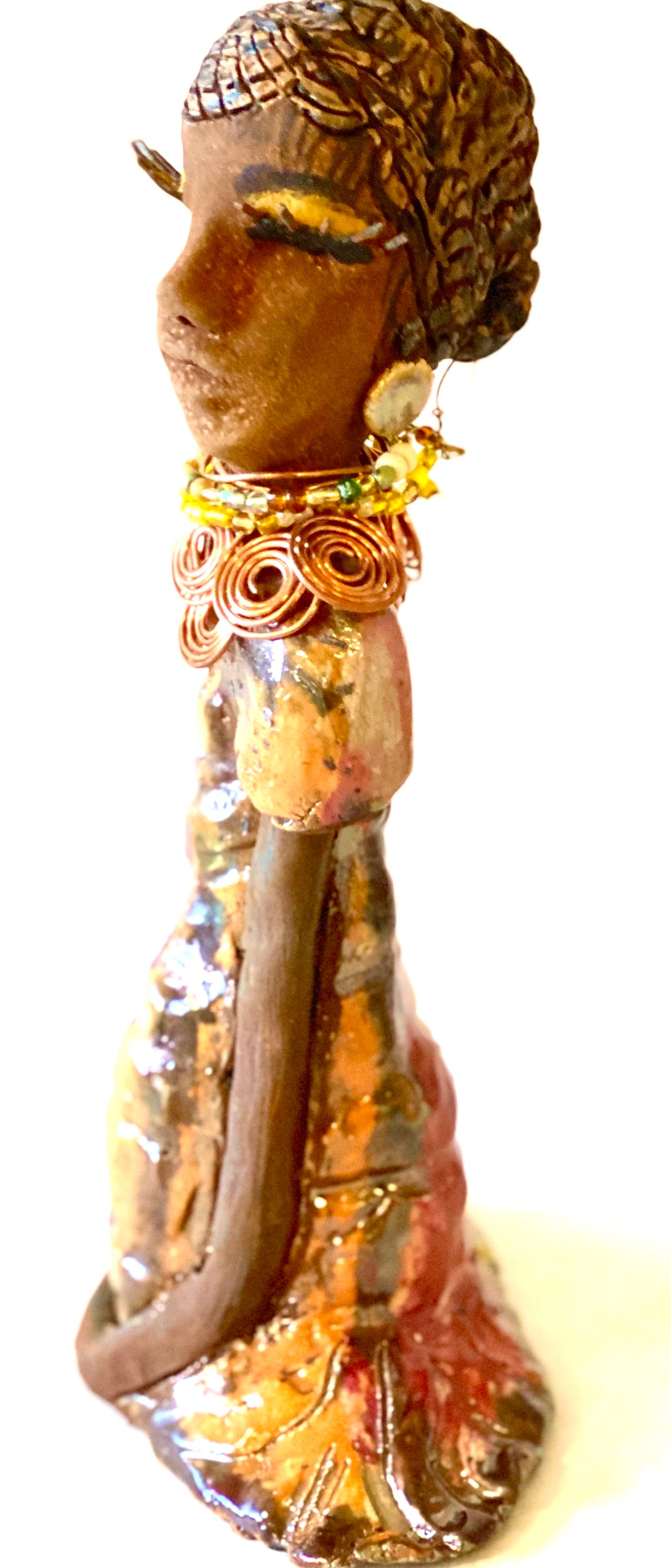 Keeba  long loving arms rest beside her multicolored metallic dress. She wears a spiral copper necklace. Keeba  is a sophisticated lady that will grace your home.