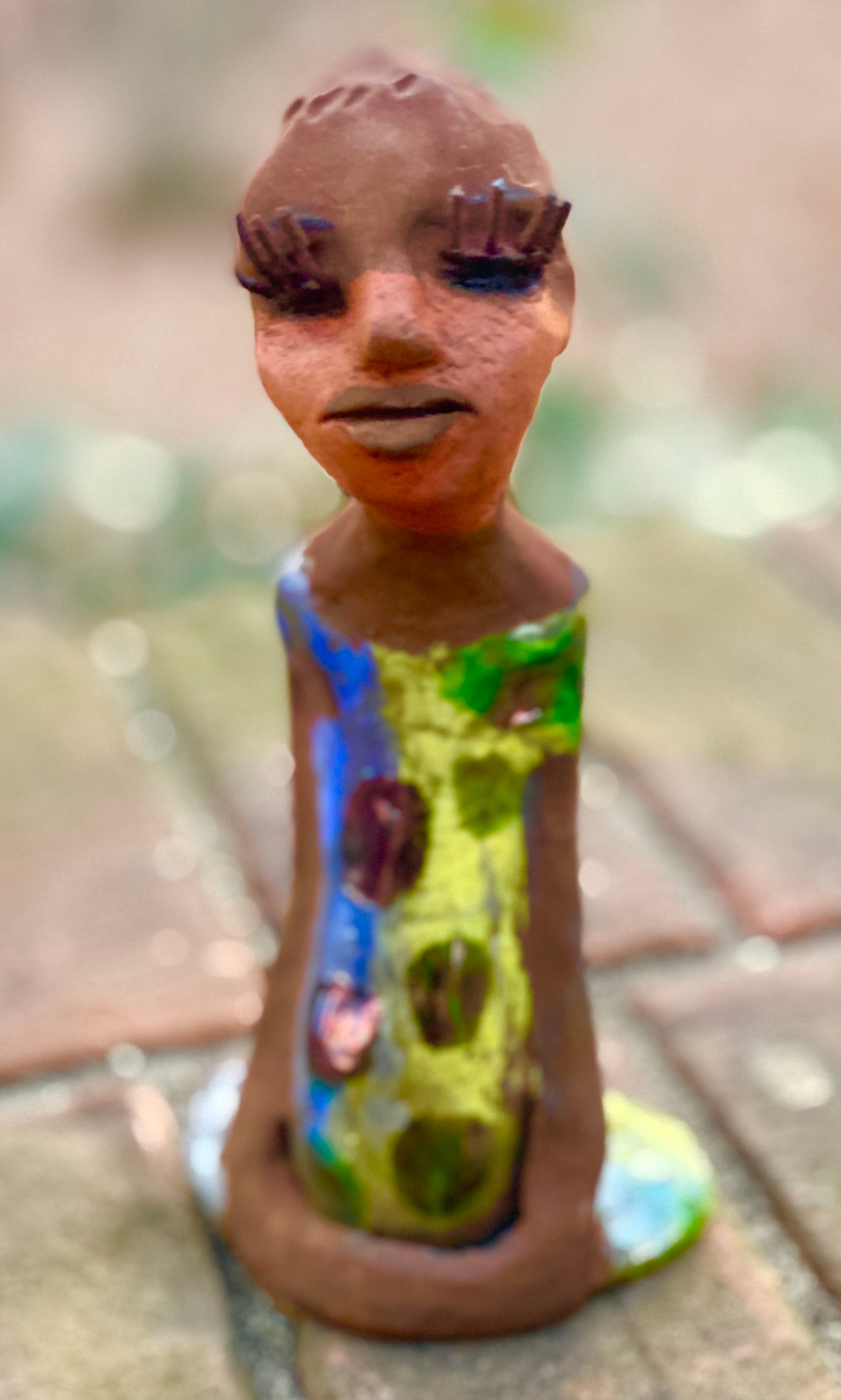 Adisa stands 7' x 4"x 2" and weighs 10.3 ozs. She has bright  dark eyes and a nice honey two tone brown complexion Her long trademark arms rest at her side. Adisa dress is a loving glossy blue and yellow mix with copper flashes.