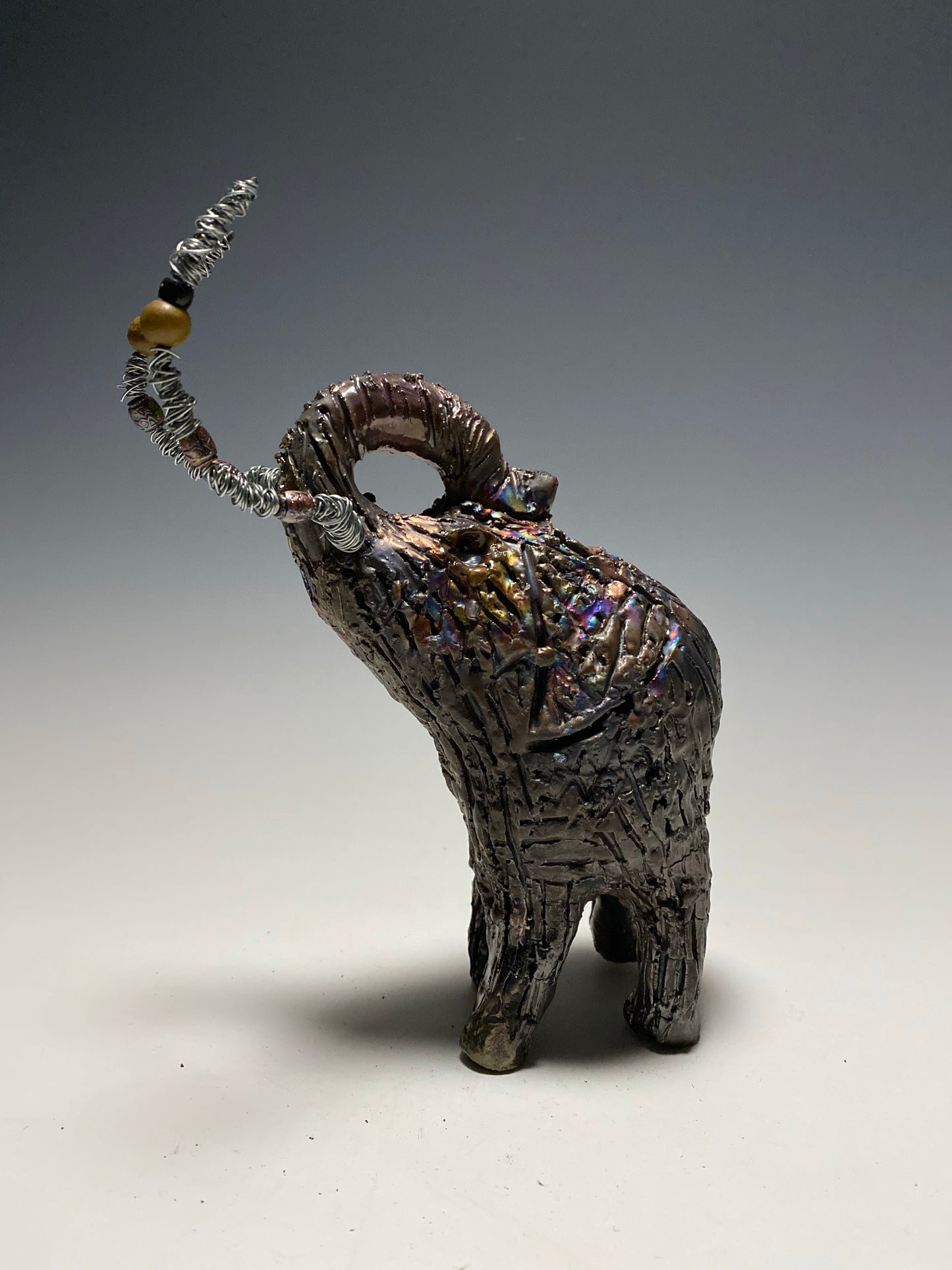 Raku Elephant Have you HERD!!!!!! Just one of these lovely Raku Fired Elephant will make an excellent gift for your friend, sorority or for your home’ special place centerpiece. 6" x 4" x 4" 1lbs Wood beaded with silver tusk Beautiful metallic raku colors For decorative purposely only.