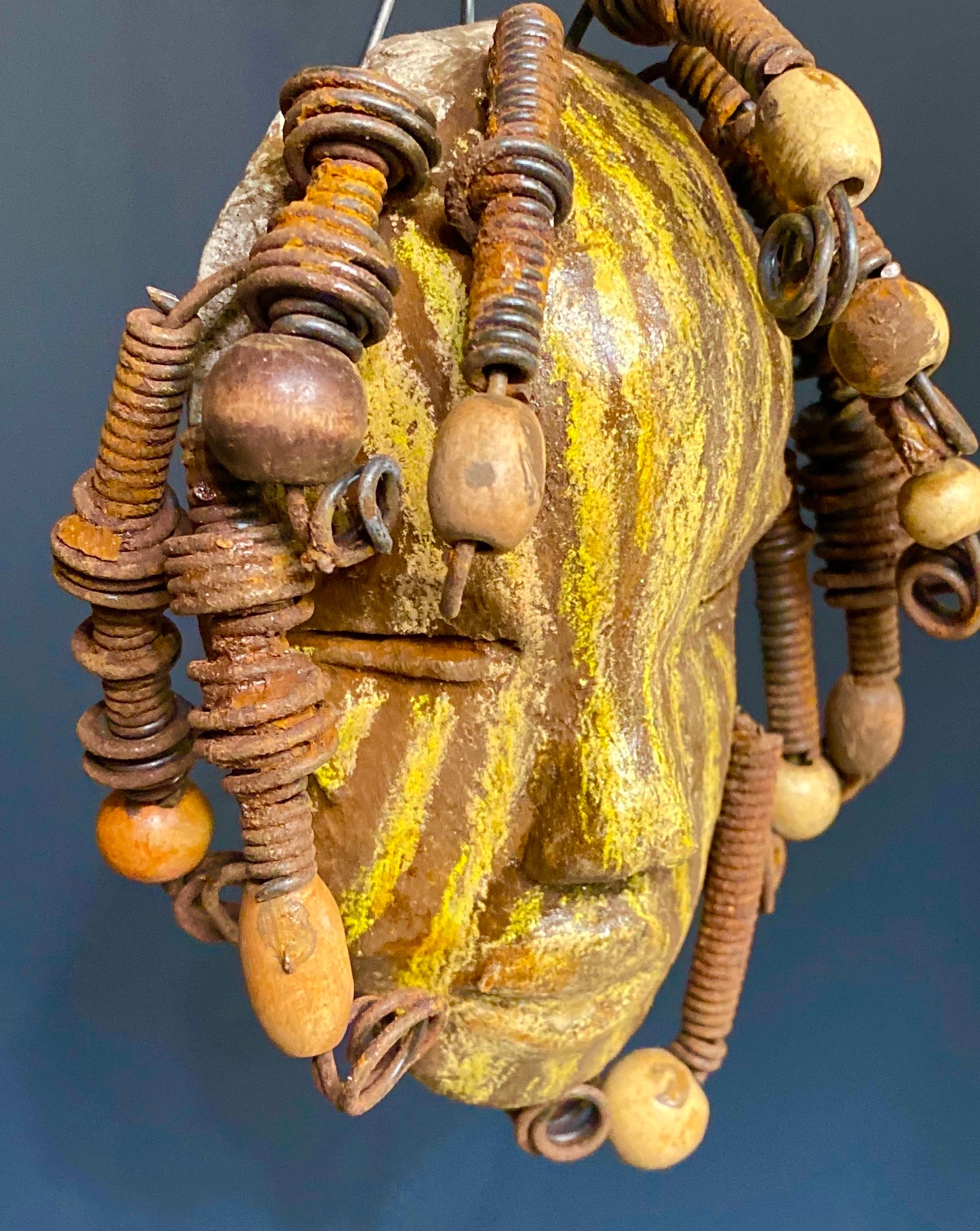 I started making art soon after seeing authentic African artwork at the Smithsonian Museum of African Art. I was in total awe. Kaba was inspired by my visit there. Kaba has a two tone striped complexion of earthy gold and brown. He is 5" x 7” and weighs 1 lbs. Kaba has over 10 wooden beads. He has over 10 feet of coiled 16 gauge wire hair. If for some reason Kaba does not fit in your home, send him back for a full refund!