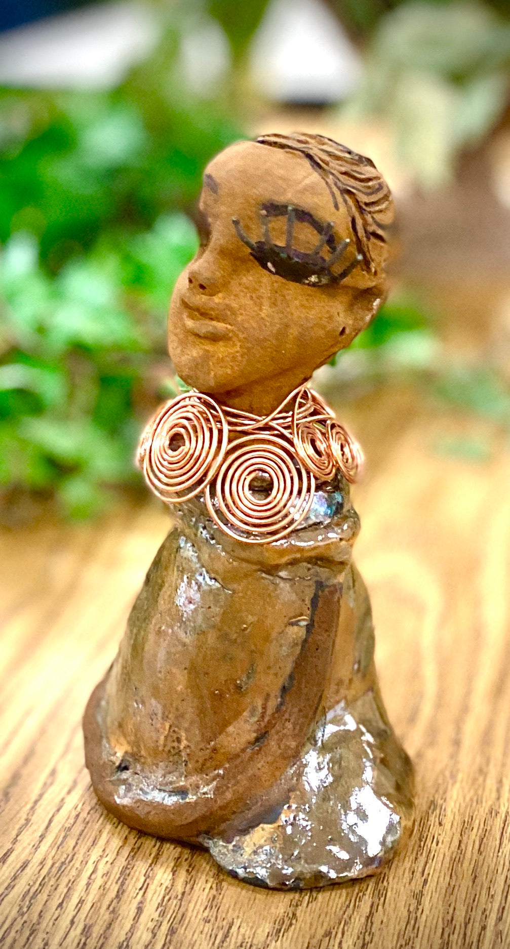Charlotte stands 7" x 5" x 4" and weighs 1.03 lbs. She has a lovely honey brown complexion with  reddish brown lips. She has a braided hairstyle.  Charlotte has a colorful metallic  yellow green antique copper glazed dress. She wears a spiral copper wire necklace. With eyes slightly opened, Charlotte has hopes of finding a new home.