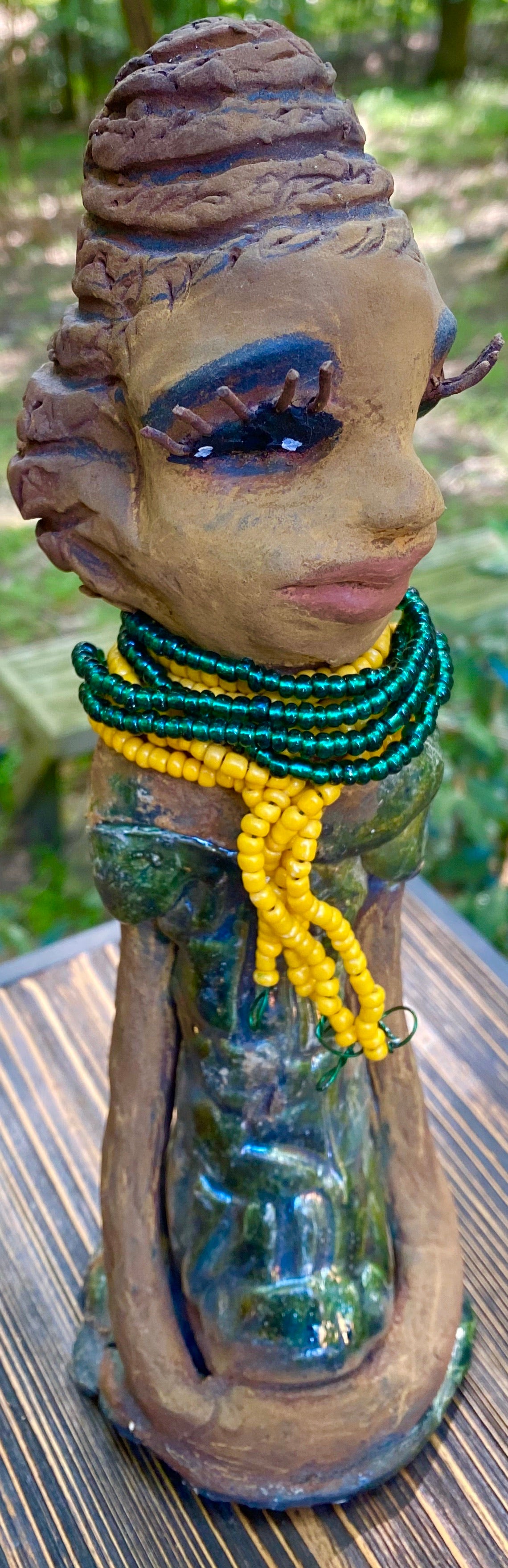 Meet Jazmyne! Jazmyne stands 11" x 4" x 4" and weighs 2.5 lbs. She has a lovely honey brown complexion with reddish brown lips. She has a braided hairstyle. Jazmyne has a colorful metallic green antique copper glazed dress. She wears a bright yellow beaded necklace. With long lashes and eyes wide opened, Jazmyne has hopes of finding a new home. Jazmyne will attract and spark conversation with guest in your home!