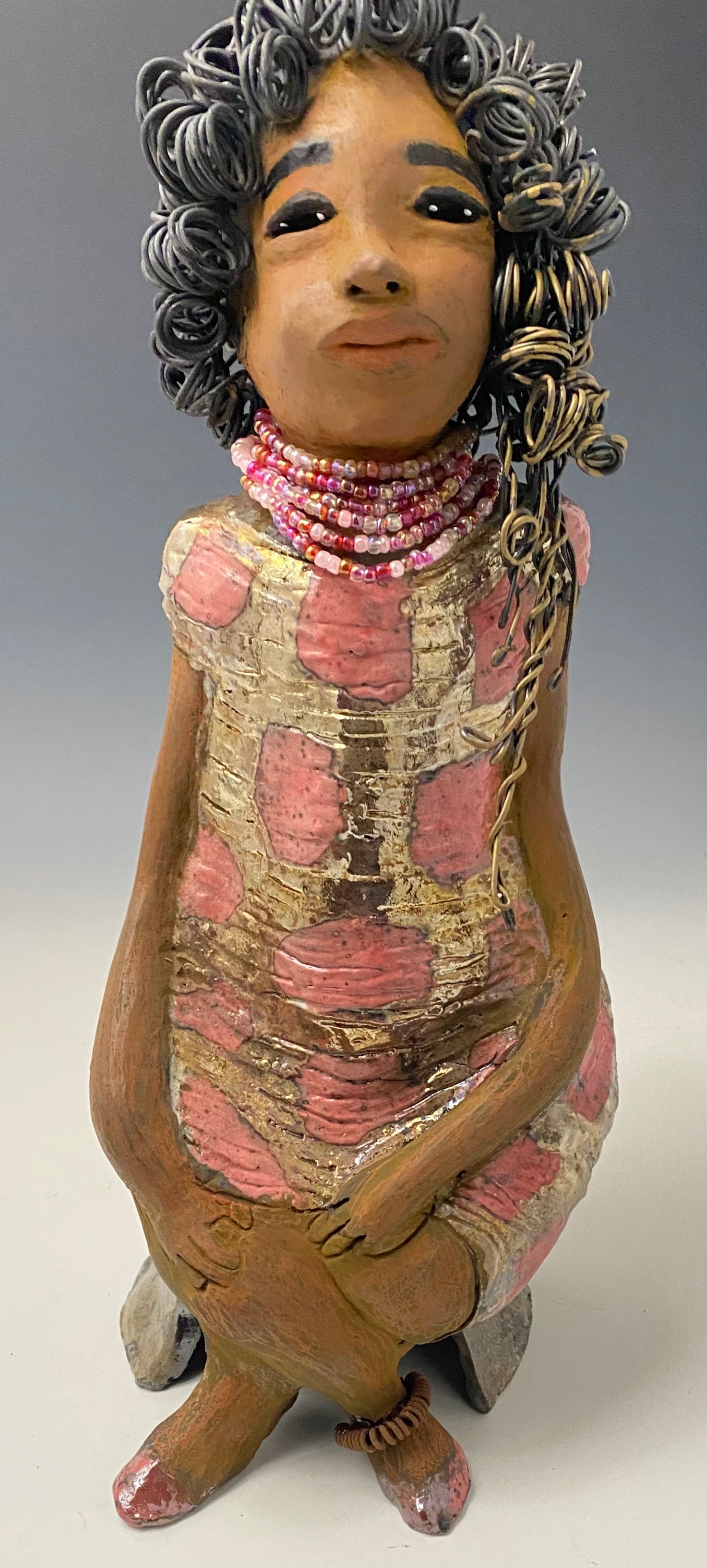 Meet Jasmine! Jasmine stands 18' x 6" x 5" and weighs 5.03 lbs. Jasmine has a lovely honey brown complexion. She has a shimmering copper red and gold dress with a red and off white beaded necklace. Jasmine is a tall girl with long loving arms. It took several hours to style Jasmine's 16 gauge two tone  wire hair! She looks as if she's dreaming or in disbelief.  I am proud of how Jasmine turned out! She appears to be a happy and sophisticated  lady!