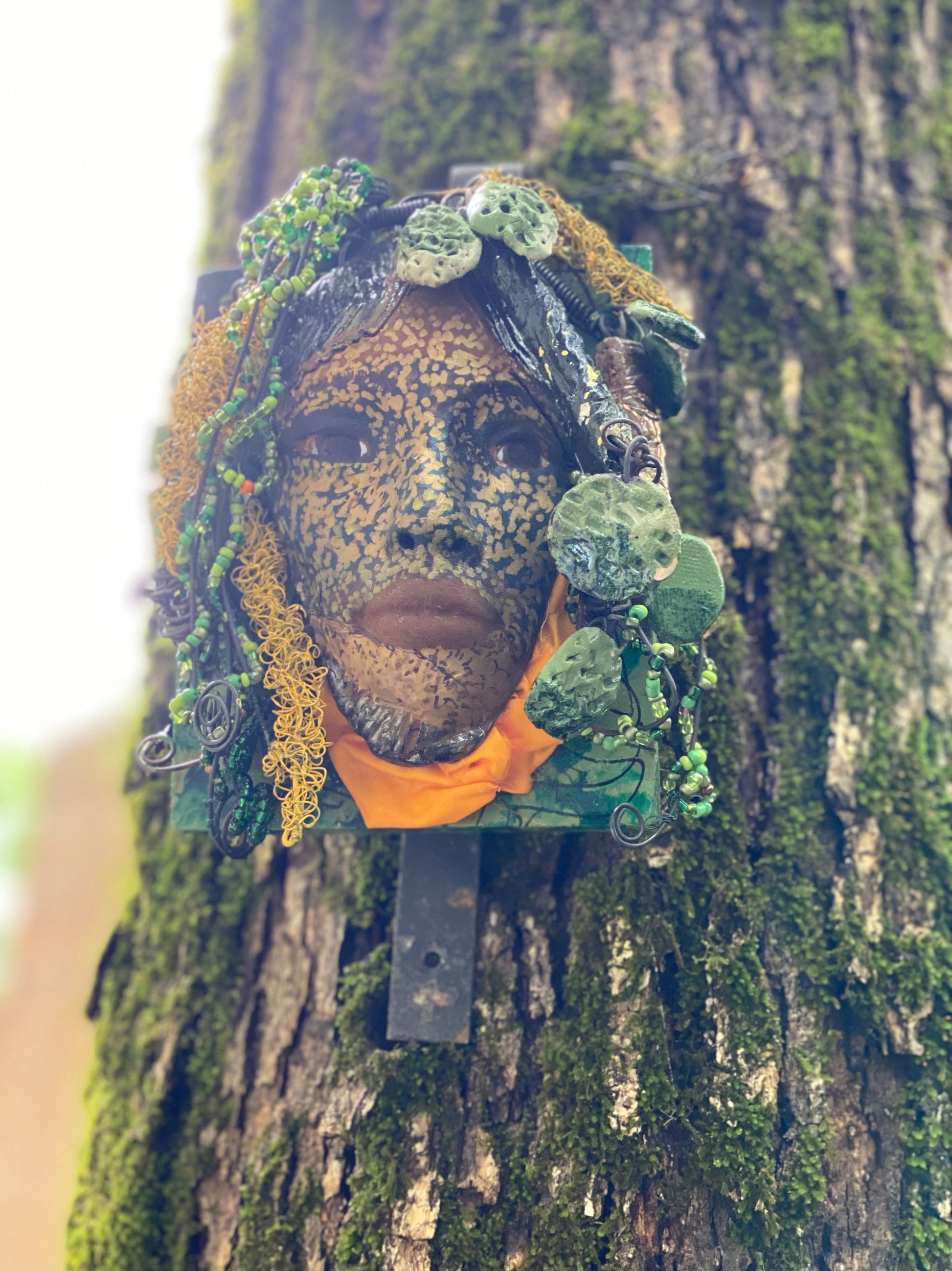 Casey is one of a new 2022  series of tribal masks that are mounted on wood. I started making art soon after seeing authentic African artwork at the Smithsonian Museum of African Art. I was in total awe. Casey is 6” x 7 x 1 and weighs 1.13 lbs.  She has a contagious smile. Casey's face is speckled gold. 12 handmade raku fired beads Over 60 mini 6mm multi colored beads  Over 60 feet of 16 and 24 gauge twisted wire for hair! Over two weeks to complete! Casey is ready to be mounted inside or outdoors!