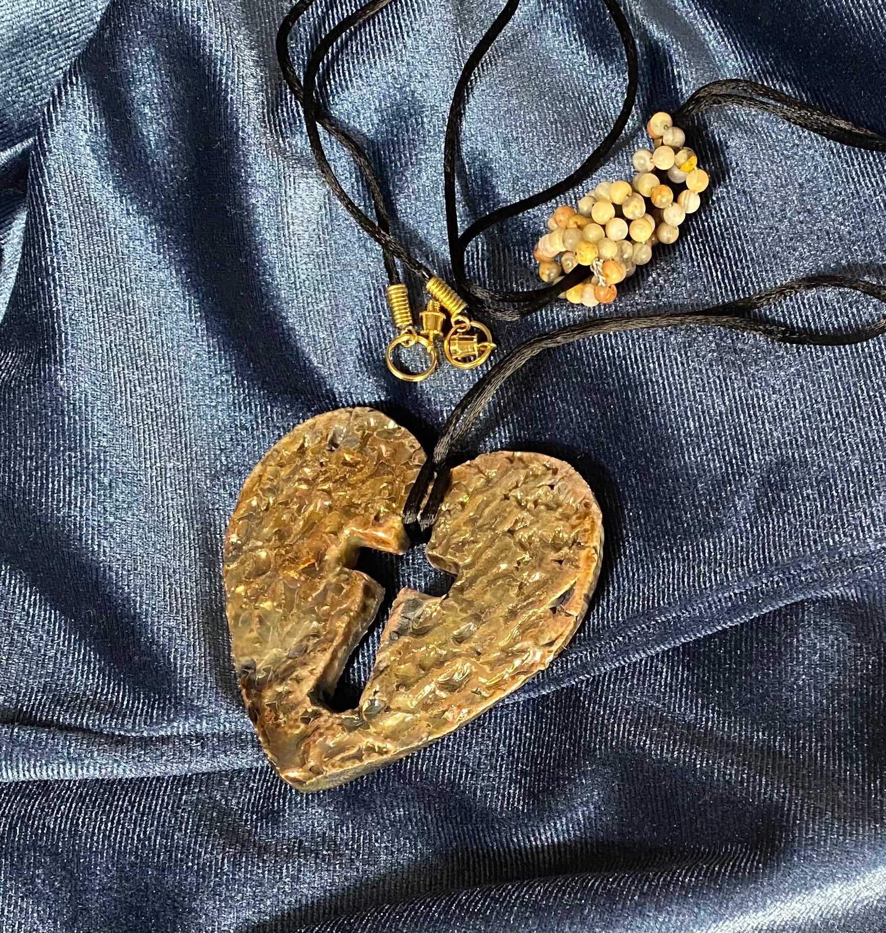 Have A Heart ! Each heart pendant is handmade with love! It is 3"x 3" and weighs approx. 3ozs. This pendant has a white and gold metallic raku glazes that renders a unique translucent  patina. The heart has a textured with cut out cross pattern . It holds a spiral of multicolored mini beads on a spiral copper wire. This pendant has a nice 12" black suede cord!