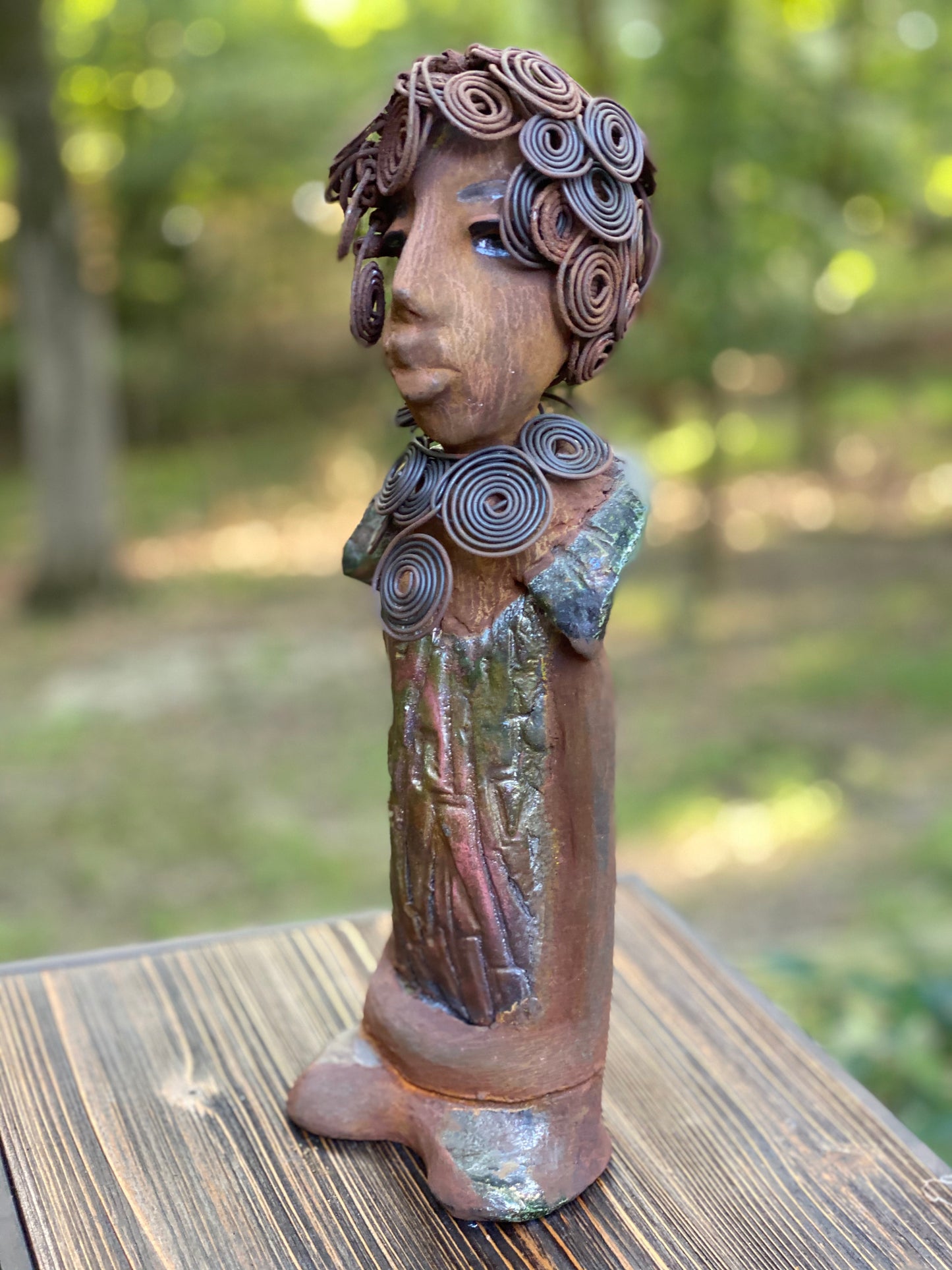 Meet Farida! Farida stand 13”x 5” x 4” and weighs 4 lbs. She has a bright eyes and a beautiful honey brown complexion. Farida has a fancy over the top Herdew. It took two hours to complete! A spiral 16 gauge necklace wraps around her neck. Her dress is a textured metallic green. Farida is looking for a new home.She would make a great gift to a BFF or just for YOU!