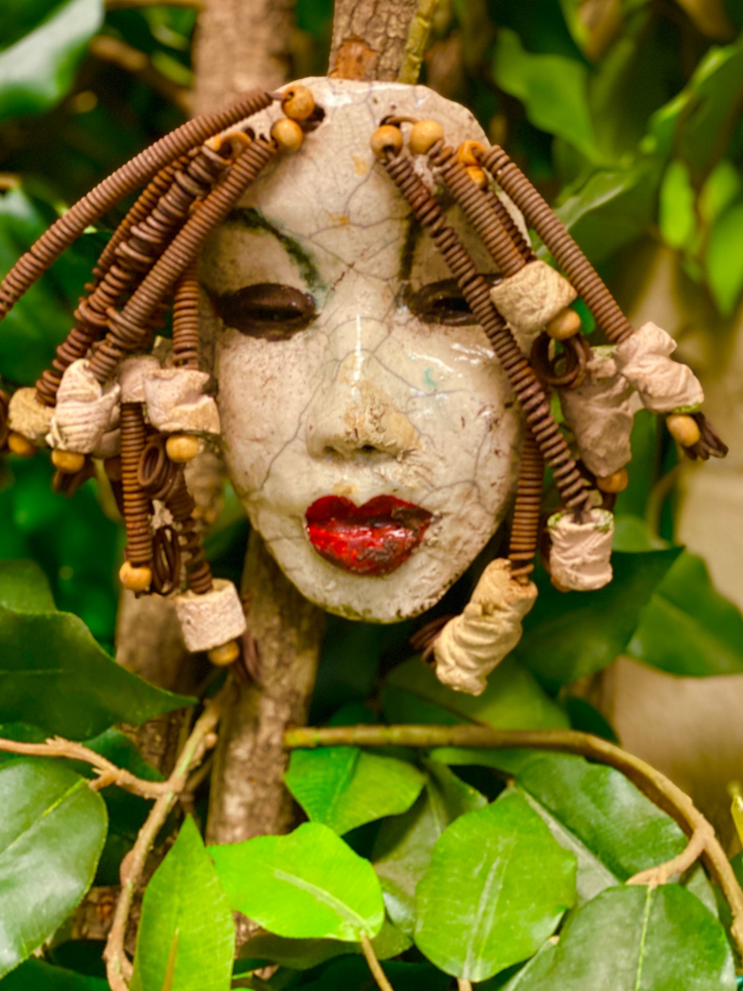 Larandra has a white crackle complexion. She is 6" x 5" and weighs 1.6 lbs. Larandra has over 20 feet of coiled 16 gauge wire hair and several wooden and white raku beads.