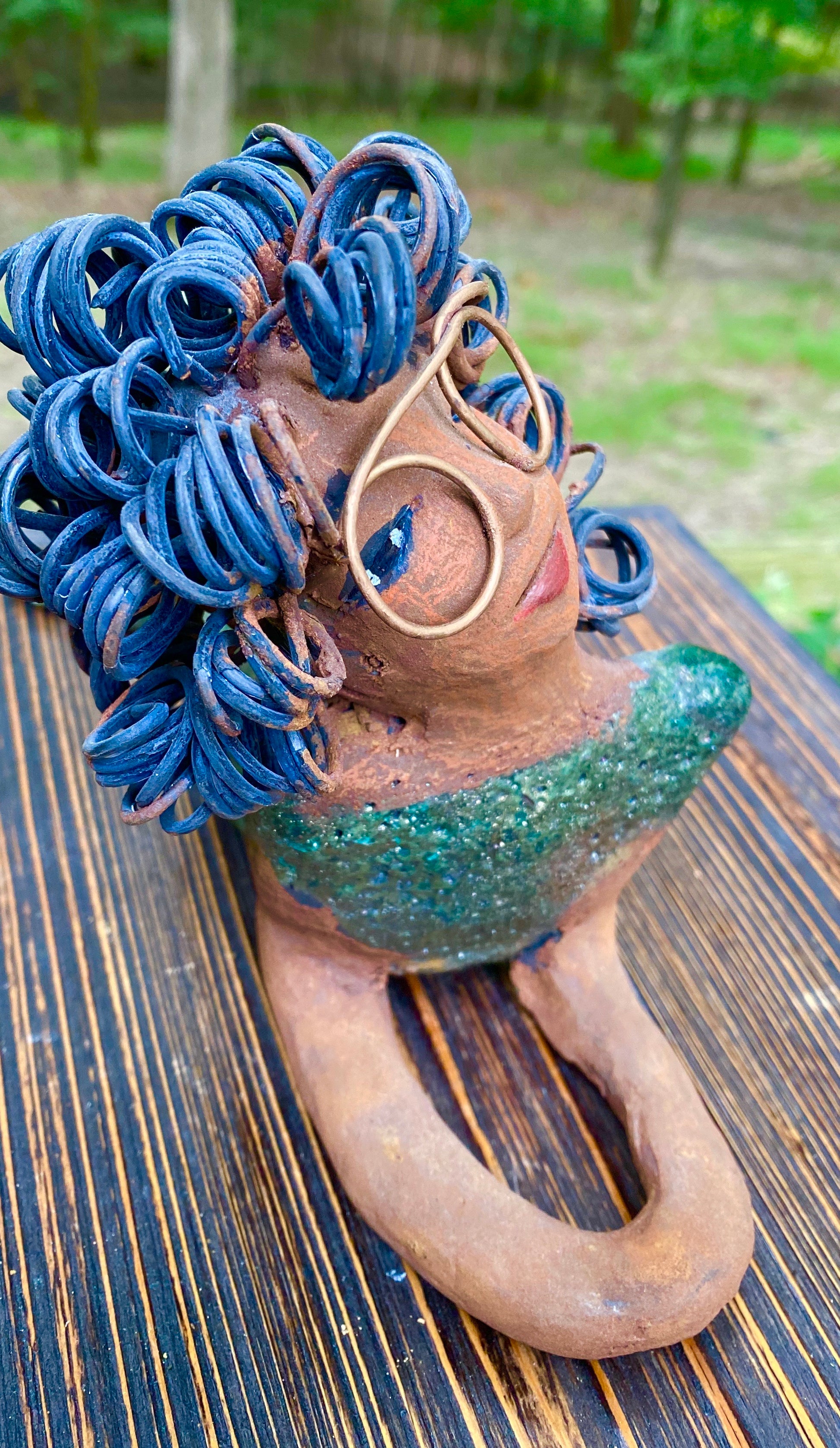 Meet Elma the Mermaid ! Elma stands 6" x 8" x 4" and weighs 1.07 lbs. Elma has a lovely honey brown complexion. Elma's body has a copper green metallic glaze She has over 25 feet of curly wire hair. Elma looks up in anticipation of being a part of your home!