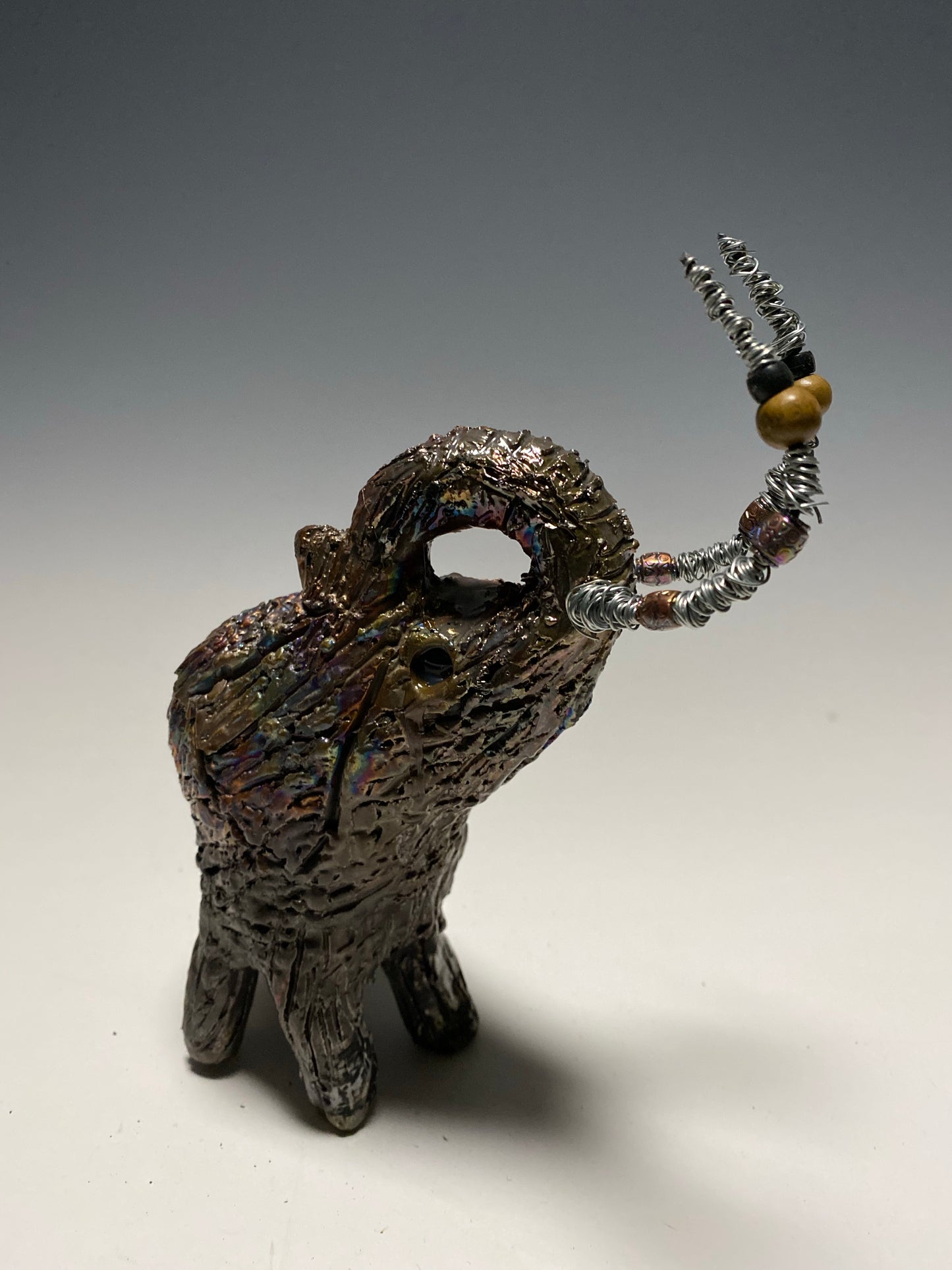 Raku Elephant Have you HERD!!!!!! Just one of these lovely Raku Fired Elephant will make an excellent gift for your friend, sorority or for your home’ special place centerpiece. 6" x 4" x 4" 1lbs Wood beaded with silver tusk Beautiful metallic raku colors For decorative purposely only.