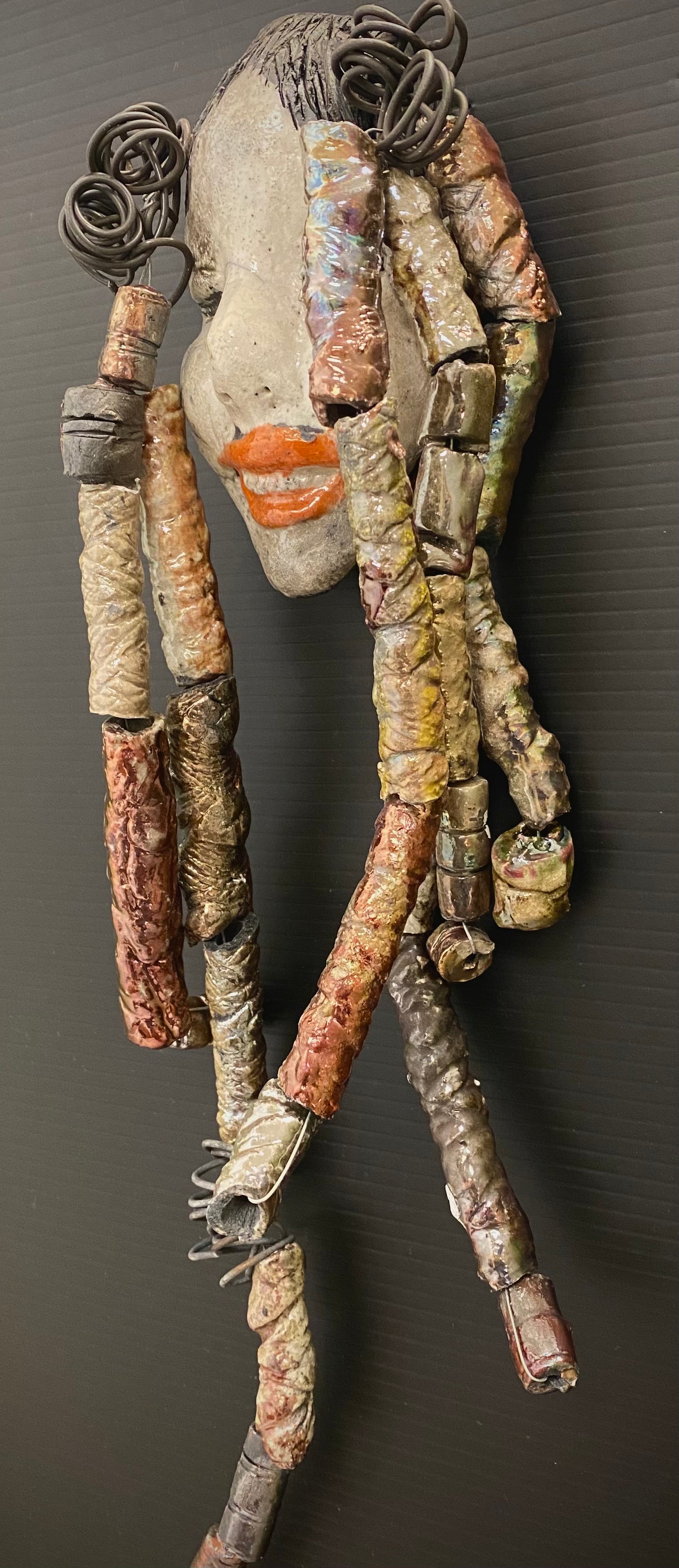 I started making art soon after seeing authentic African artwork at the Smithsonian Museum of African Art. I was in total awe. Trinity was inspired by my visit there. Trinity is 5”x 13” and weighs 11ozs. She has an off white complexion with ruby red lips. Trinity has five dreads of beads and spiral wire coils of hair. She is ready to be installed in your home!