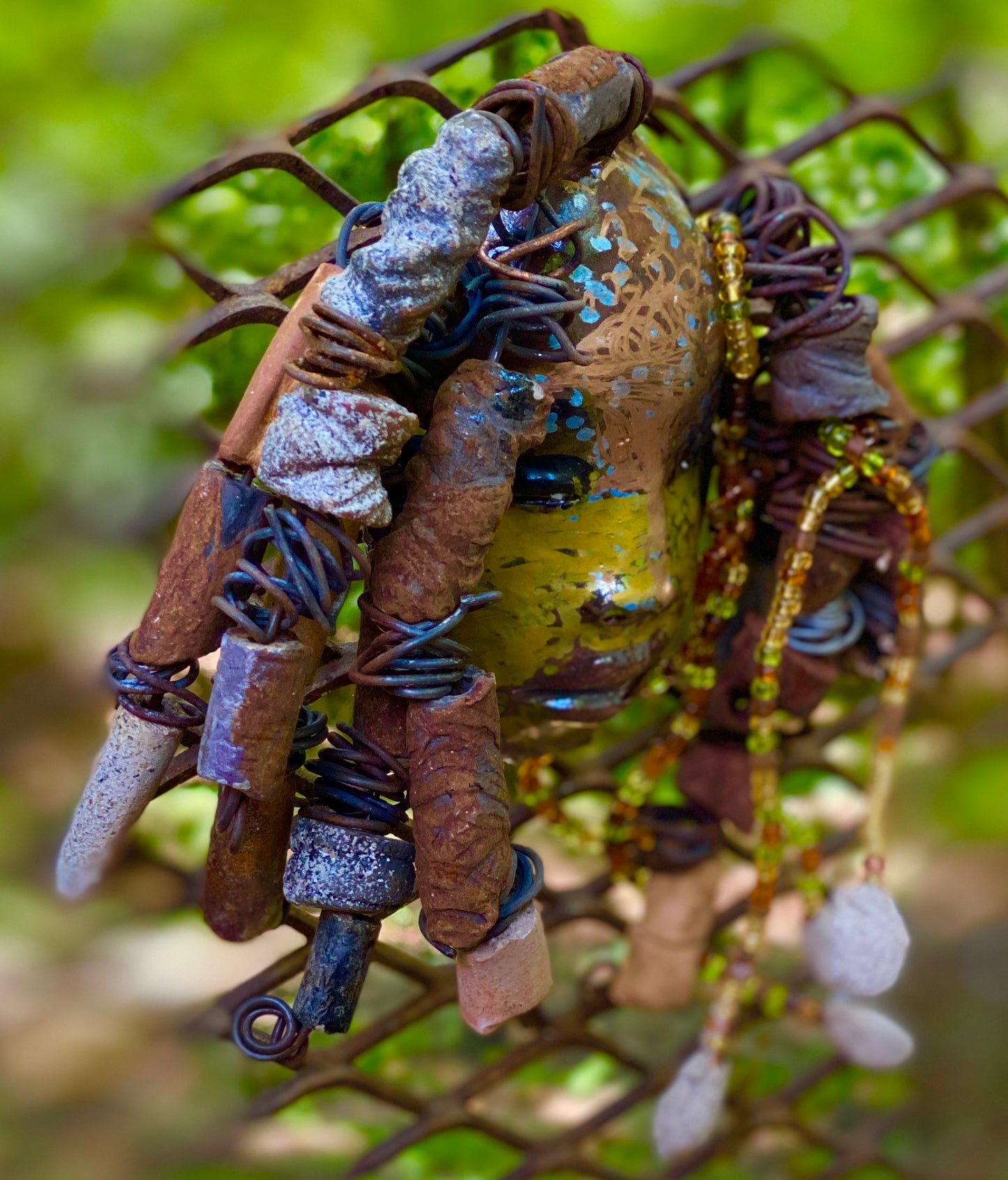 I started making mask soon after seeing authentic African artwork at the Smithsonian Museum of African Art. I was in total awe. Marali means she who listen was inspired by my visit there. Marali has a two tone metallic blue copper gold complexion. She is 7" x 5" and weighs 14 ozs. Marali has over 20 handmade raku fired beads. She has over 50 mini amber bead twisted as hair. Marali has over 6 feet of copper coiled 16 gauge wire hair.