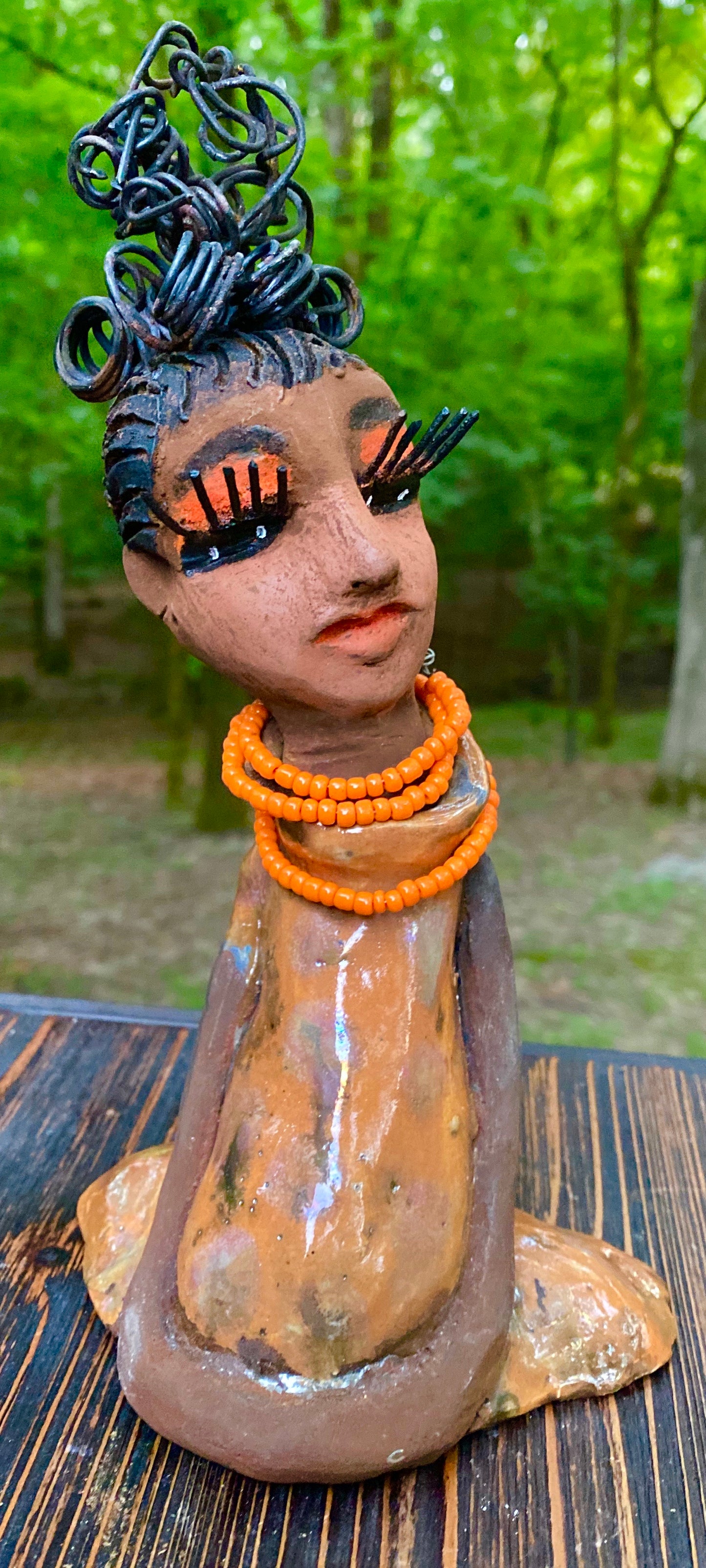 Meet Abimbola ! Abimbola stands 7' x 4"x 2" and weighs 1.3 lb. She has bright eyes and a nice honey brown complexion Abimbola  has over 5 feet of 16 gauge wire hair wrapped in a bun. Her long trademark arms rest at her side. Abimbola dress is a loving glossy orange mix with copper flashes. Abimbola is waiting for you to invite her into your home!