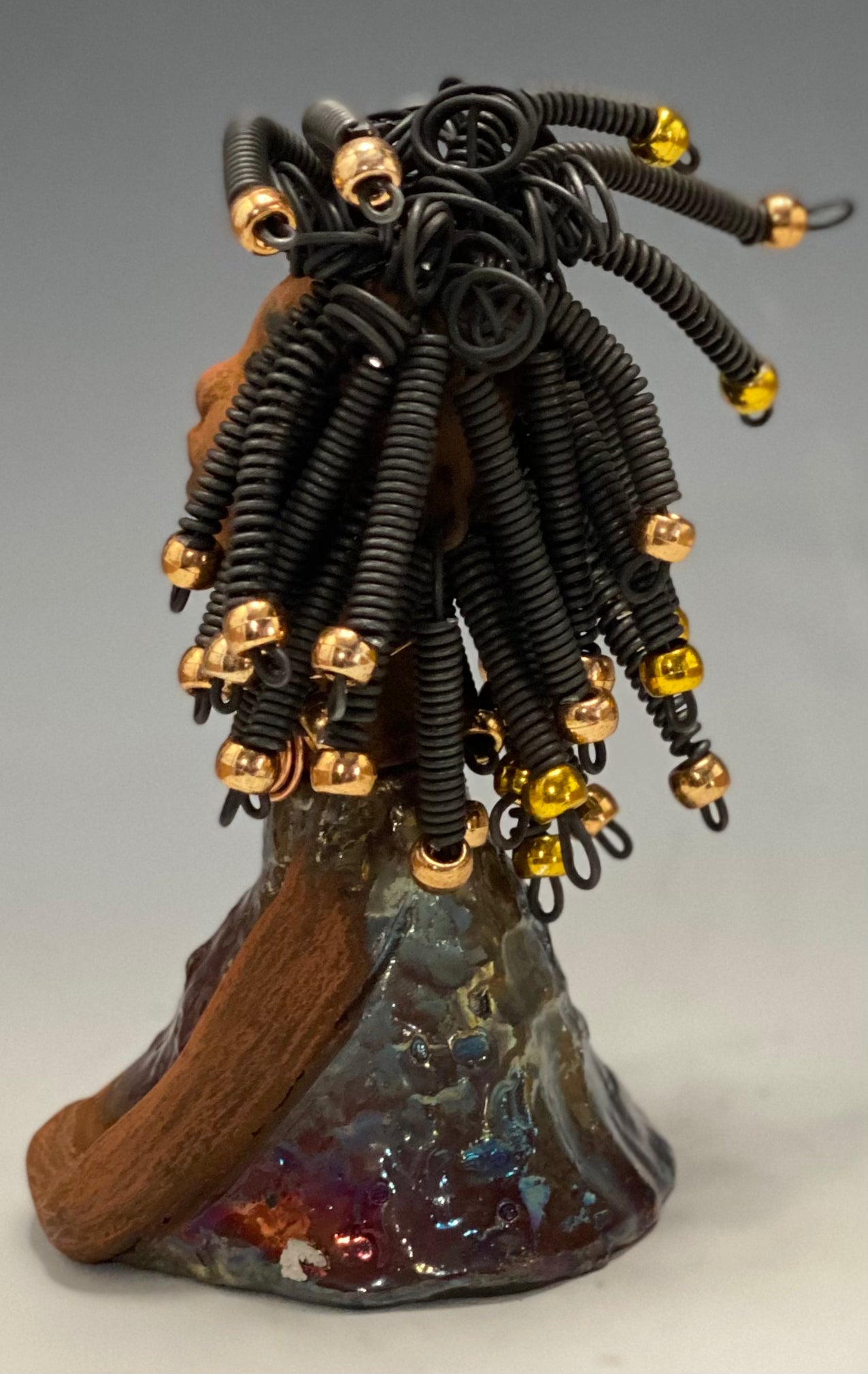 Meet Alexus Alexus stands 7.5" x 4" x 4" and weighs 1.05 lbs. She wears a lovely glossy metallic gold dress adorn by a spiral copper necklace. Alexus has over15 feet of coiled wire hair with gold beads.. Alexus appears to sit in a yoga pose. Her long arms rest at her side. Alexus is a great starter piece from the Herdew Collection!