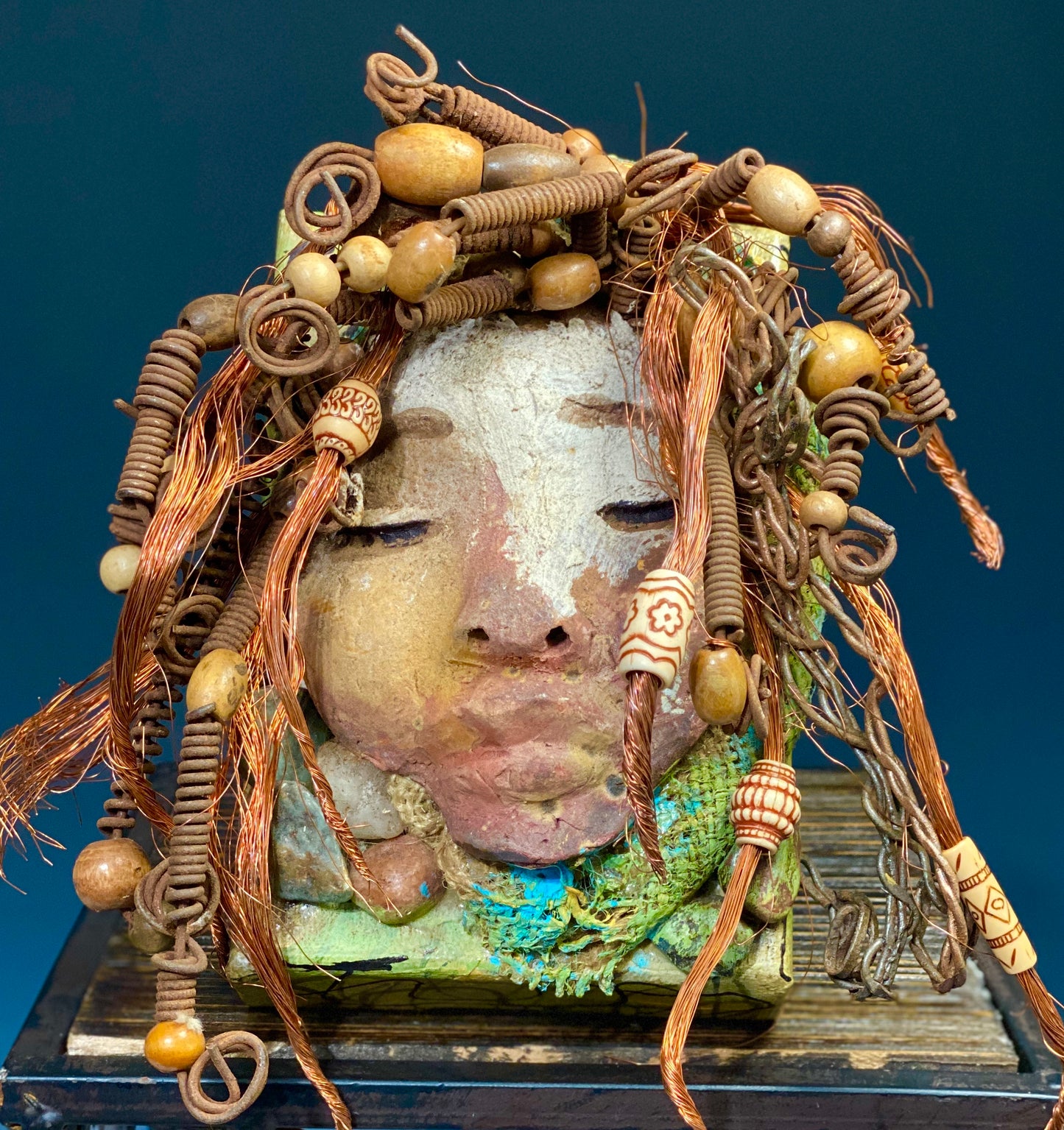 I started making art soon after seeing authentic African artwork at the Smithsonian Museum of African Art. I was in total awe. Lulu was inspired by my visit there. Lulu is uniquely mounted on a painted 6"x 4"x 2" canvas. It weighs 1.15 lbs. Her face has a two tone off white and earthy crackle glaze. Lulu has hand coiled wire, white and multi color beads, textured earthy cloth..