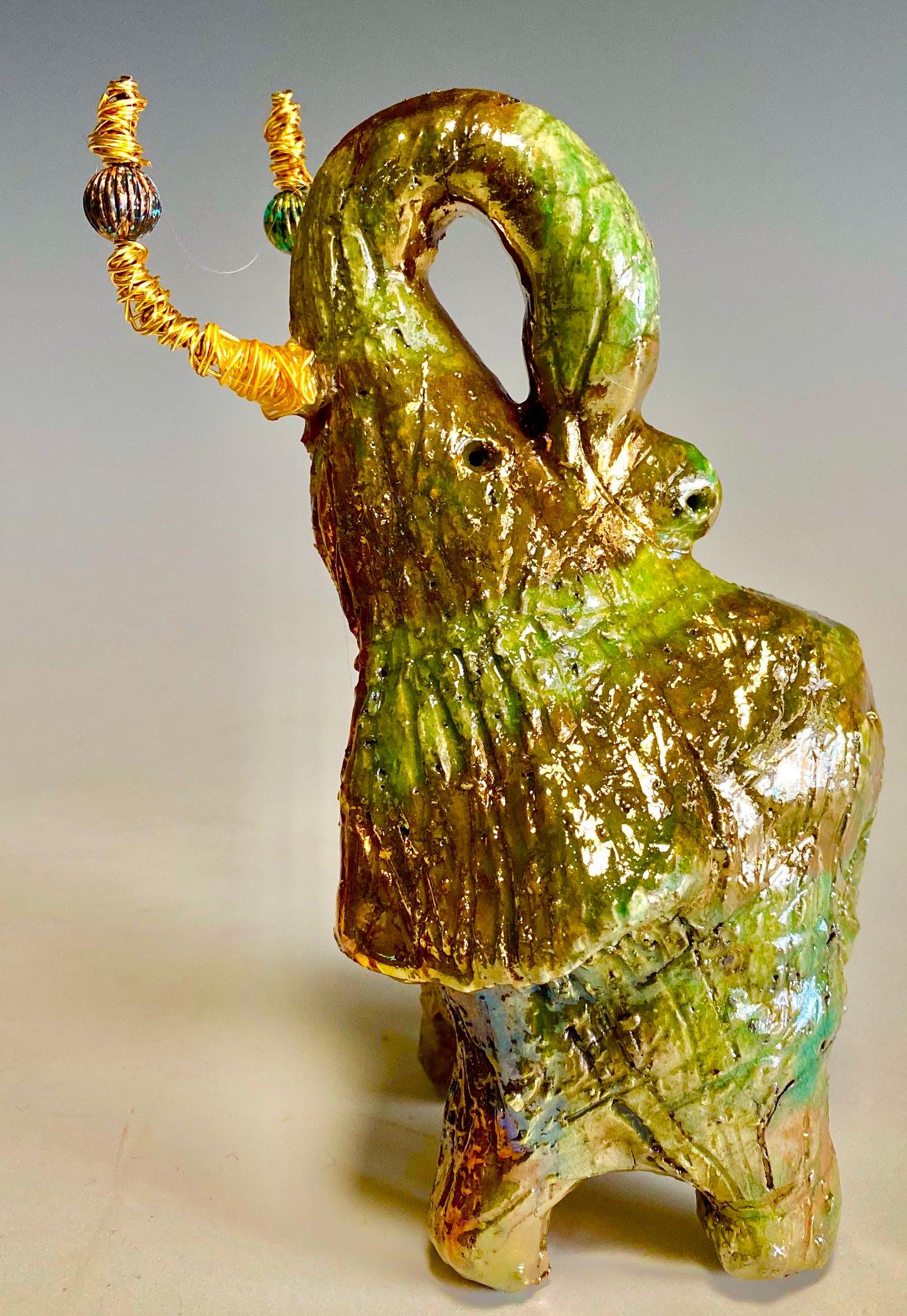 Raku Elephant Have you HERD!!!!!! Just one of these lovely Raku Fired Elephant will make an excellent gift for your friend, sorority or for your home’ special place centerpiece. 6" x 4" x 5" 14 ozs. Beautiful copper, green and gold metallic raku elephant Gold beaded tusk For decorative purposely only.