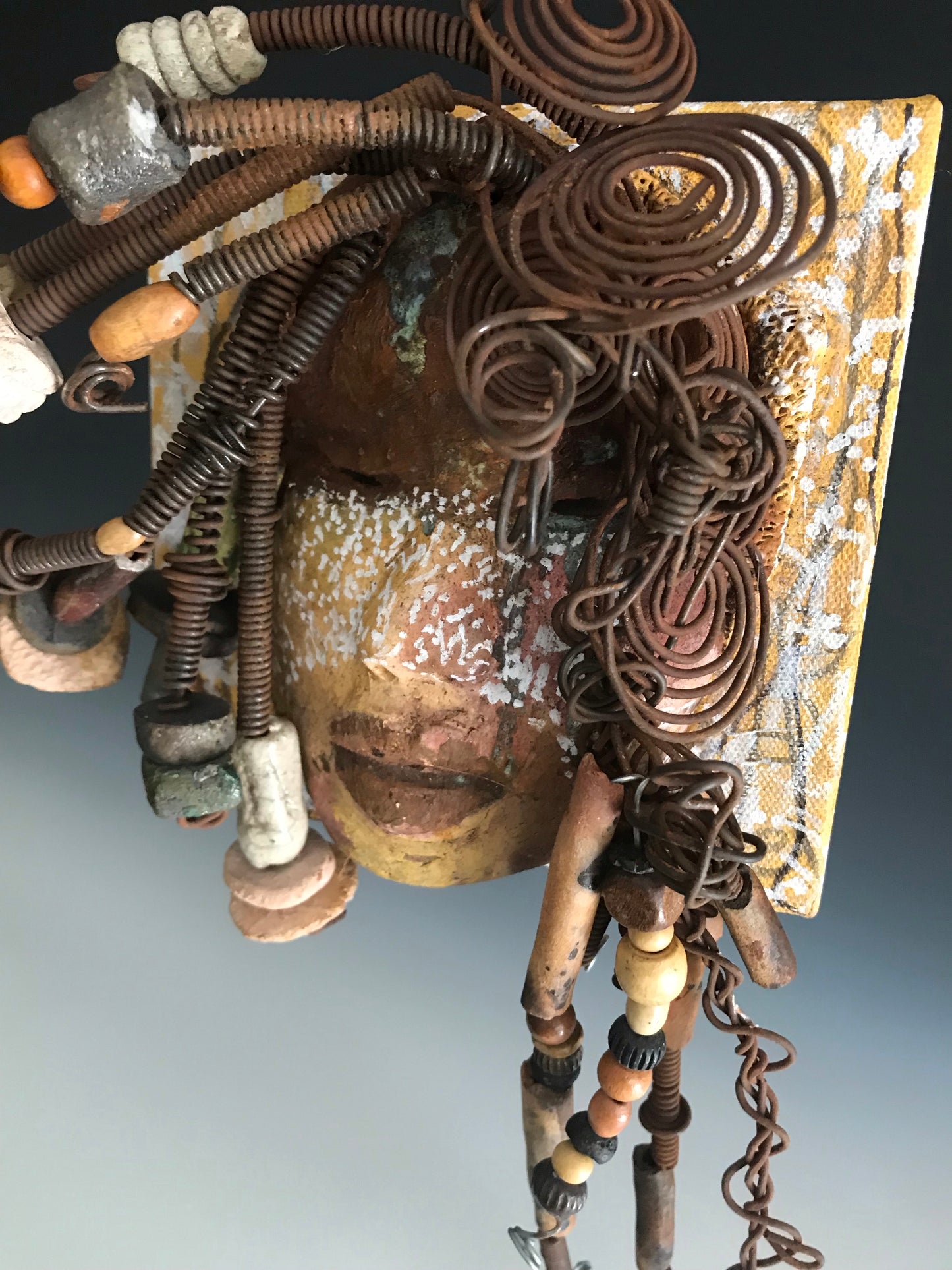 Iowa is uniquely mounted on a painted 6"x 4"x 2" canvas. It weighs 1.13 lbs. Her face has white dots over an earthy.glaze with dark brown lips. Iowa has hand coiled wire, multi color raku beads,wood beads, and textured earthy cloth.. Iowa is ready to be hung!