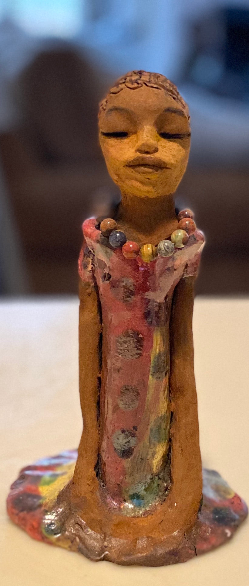 Mena long loving arms rest beside her multicolored copper green dress. Mena is a sophisticated lady that will grace your home.
