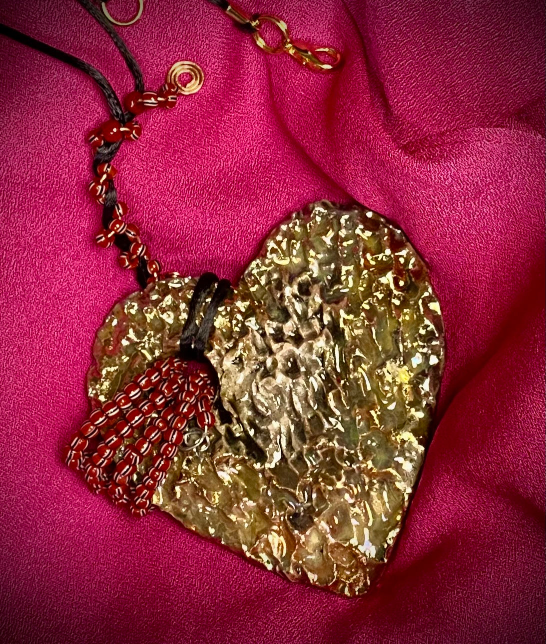 Have A Heart ! Each heart pendant is handmade with love! It is 3"x 3" and weighs approx. 3ozs. This pendant has a white and gold metallic raku glazes that renders a unique translucent  patina. The heart has a textured with cut out cross pattern . It holds a spiral of multicolored mini beads on a spiral copper wire. This pendant has a nice 12" black suede cord!
