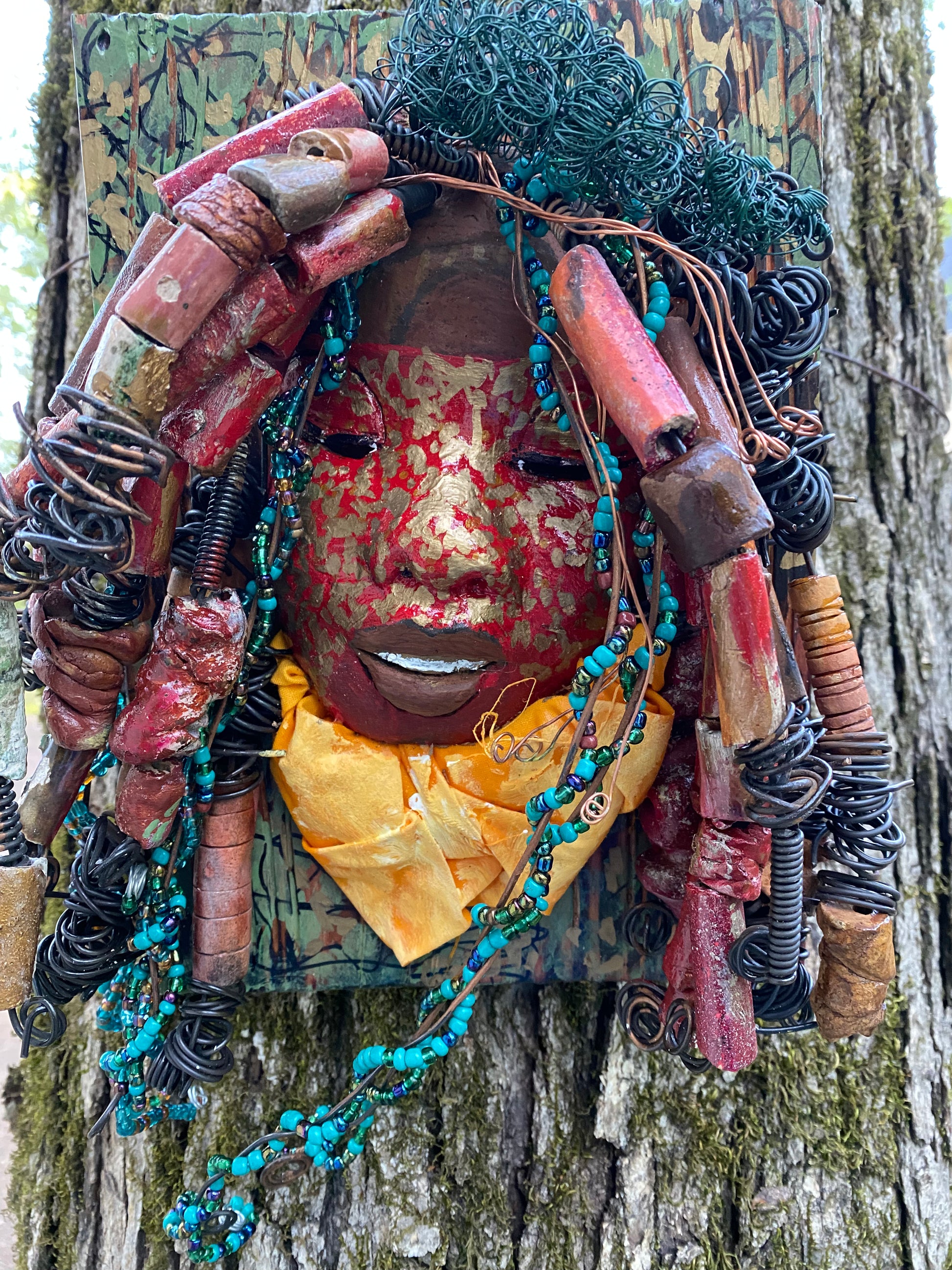 Deandra is one of a new 2022  series of tribal masks that are mounted on wood. I started making art soon after seeing authentic African artwork at the Smithsonian Museum of African Art. I was in total awe. Deandra is 7” x 10 x 1 and weighs 3.7 lbs.  She has a contagious smile. 25 handmade raku fired beads Over 60 mini 6mm multi colored beads  Over 60 feet of 16 and 24 gauge twisted wire for hair!