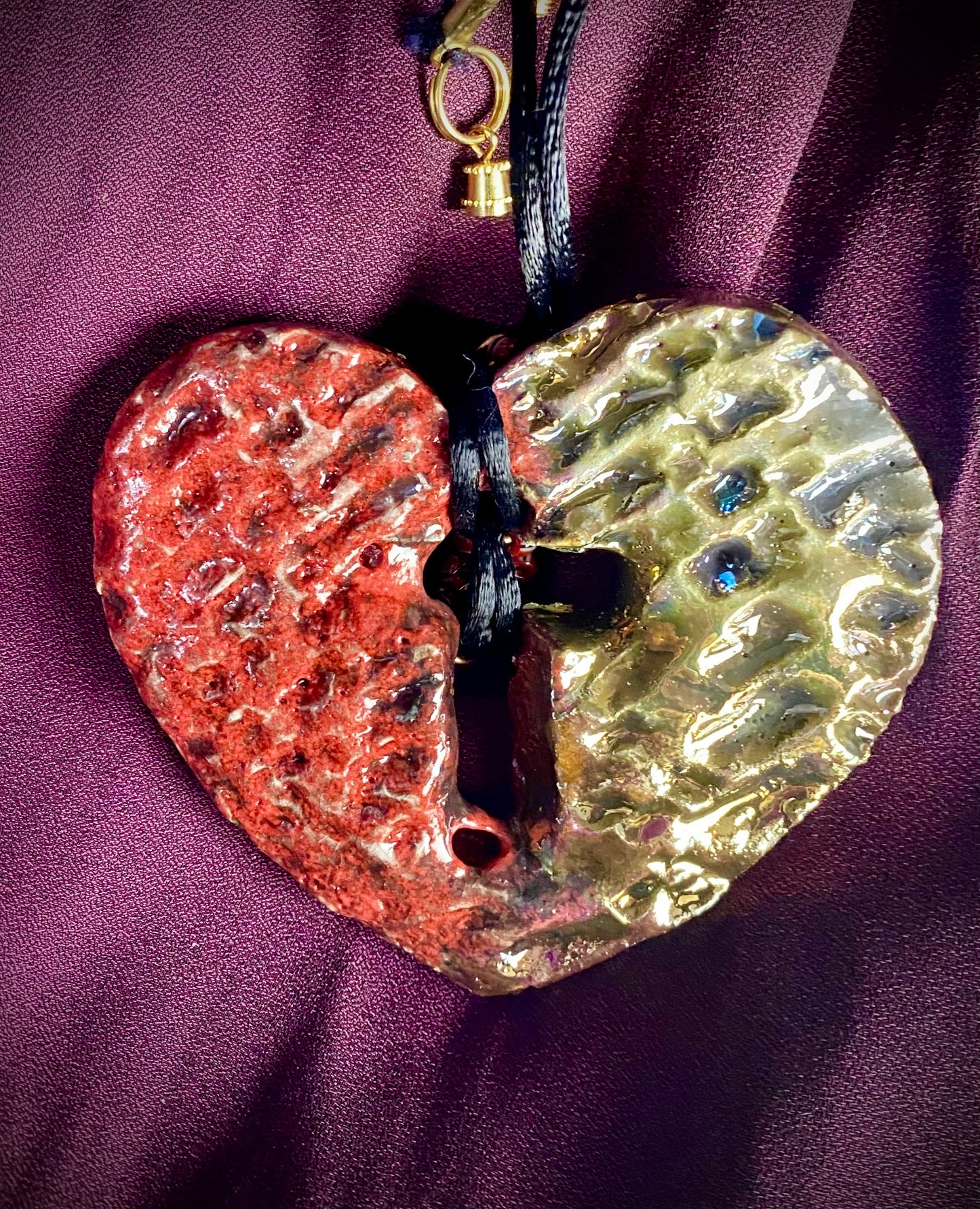 Have A Heart ! Each heart pendant is handmade with love! It is 3"x 3" and weighs approx. 3ozs. This pendant has a ruby red and gold metallic raku glazes that renders a unique translucent patina. The heart has a textured pattern with a cut out cross in the center.. It holds a spiral of ruby red mini beads on a spiral copper wire. This pendant has a nice 12" black suede cord!
