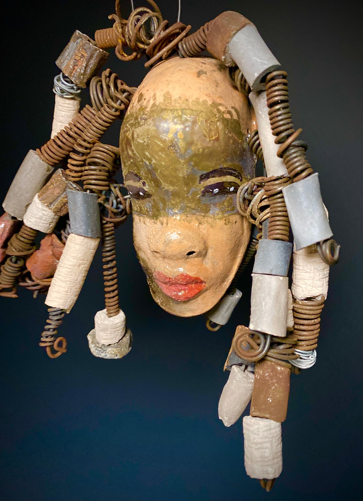 I started making art soon after seeing authentic African artwork at the Smithsonian Museum of African Art. I was in total awe. Kia was inspired by my visit there. Kia has a light and dark honey brown complexion. Her hair can be adjusted up to 11" x 10" and weighs 1.09 lbs Kia has over 20 handmade multicolored raku fired beads. She has over 20 feet of coiled 16 gauge wire hair. Kia is ready for display!