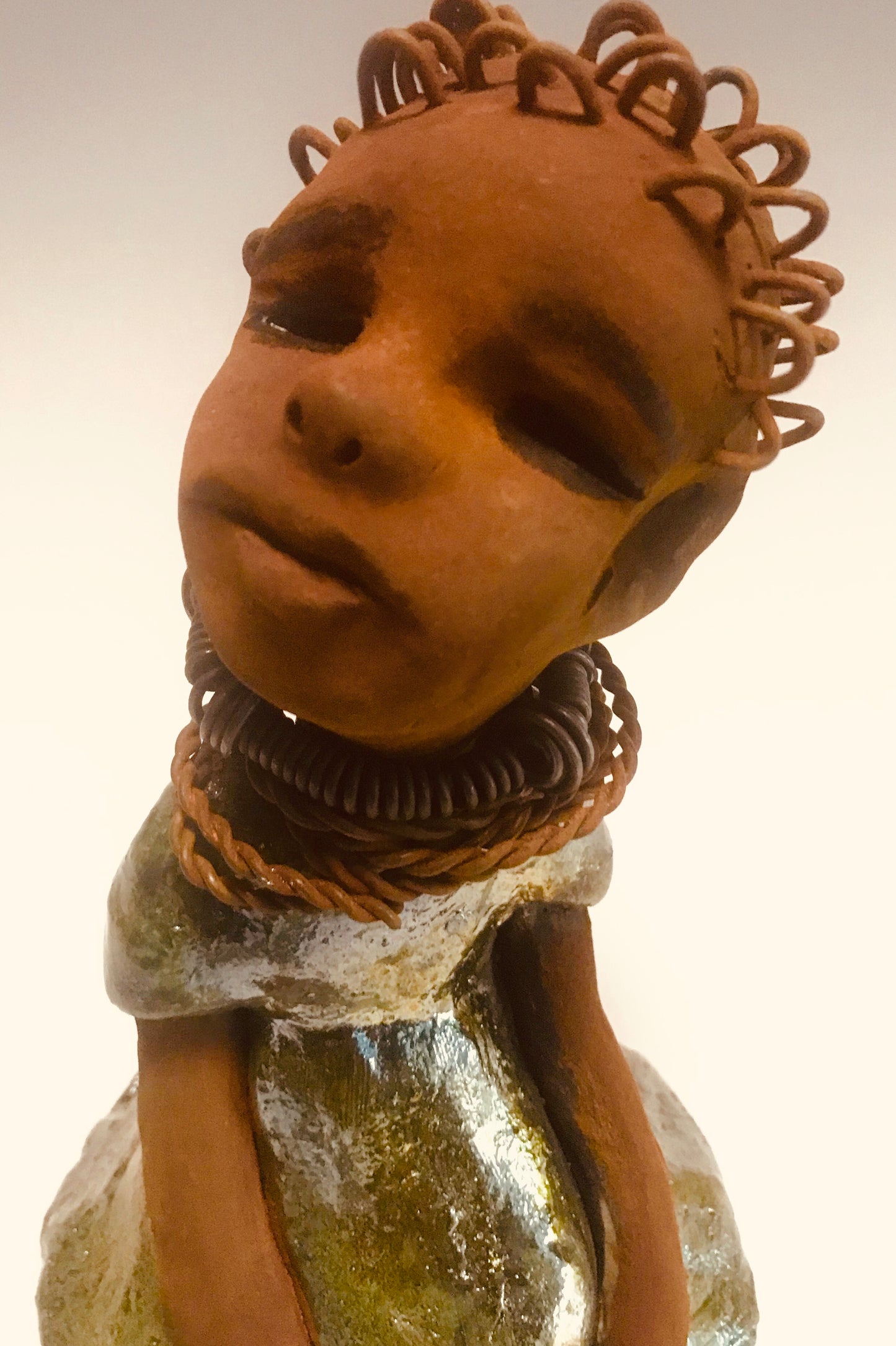 Nura stands 7.5" x 5" x 5" and weighs 1.06 lbs. She has a lovely honey brown complexion with reddish brown lips. She has a wire braided hairstyle. Nura has a colorful metallic green antique copper glazed dress. She wears spiral wire necklaces With her eyes wide opened, Nura has hopes of finding a new home.
