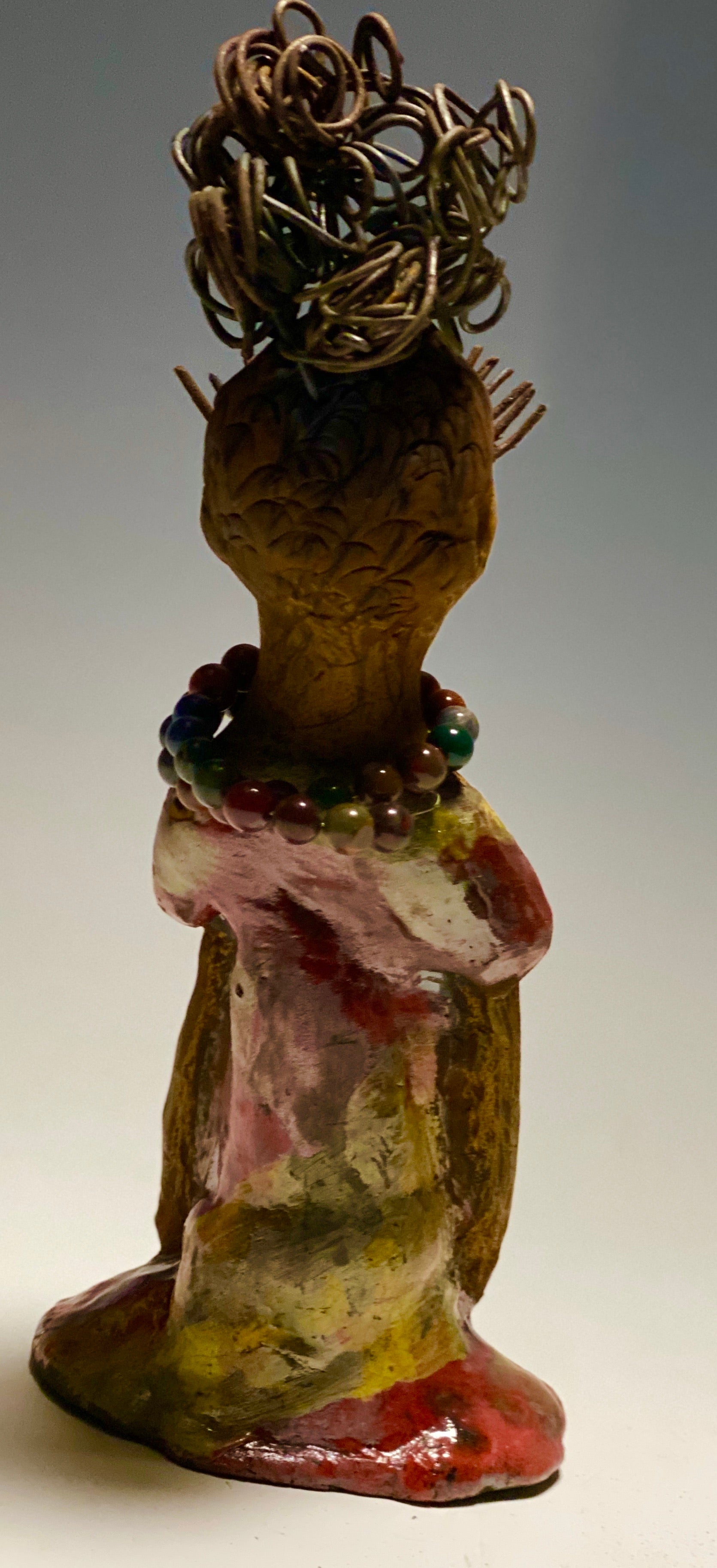 You know someone like Tiffanie. One who reaps elegance and sophistication!  Tiffanie stands 9”x 4" x 4" and weighs 1.03 lbs.  She has a two tone light beige complexion with 2 feet of 16 gauge spiral coiled wire hair.  Tiffanie metallic copper red and yellow  dress is accented by a multicolored beaded necklace. Tiffanie’s long lashes and  black eye shadow gives her a distinguished mystical look.