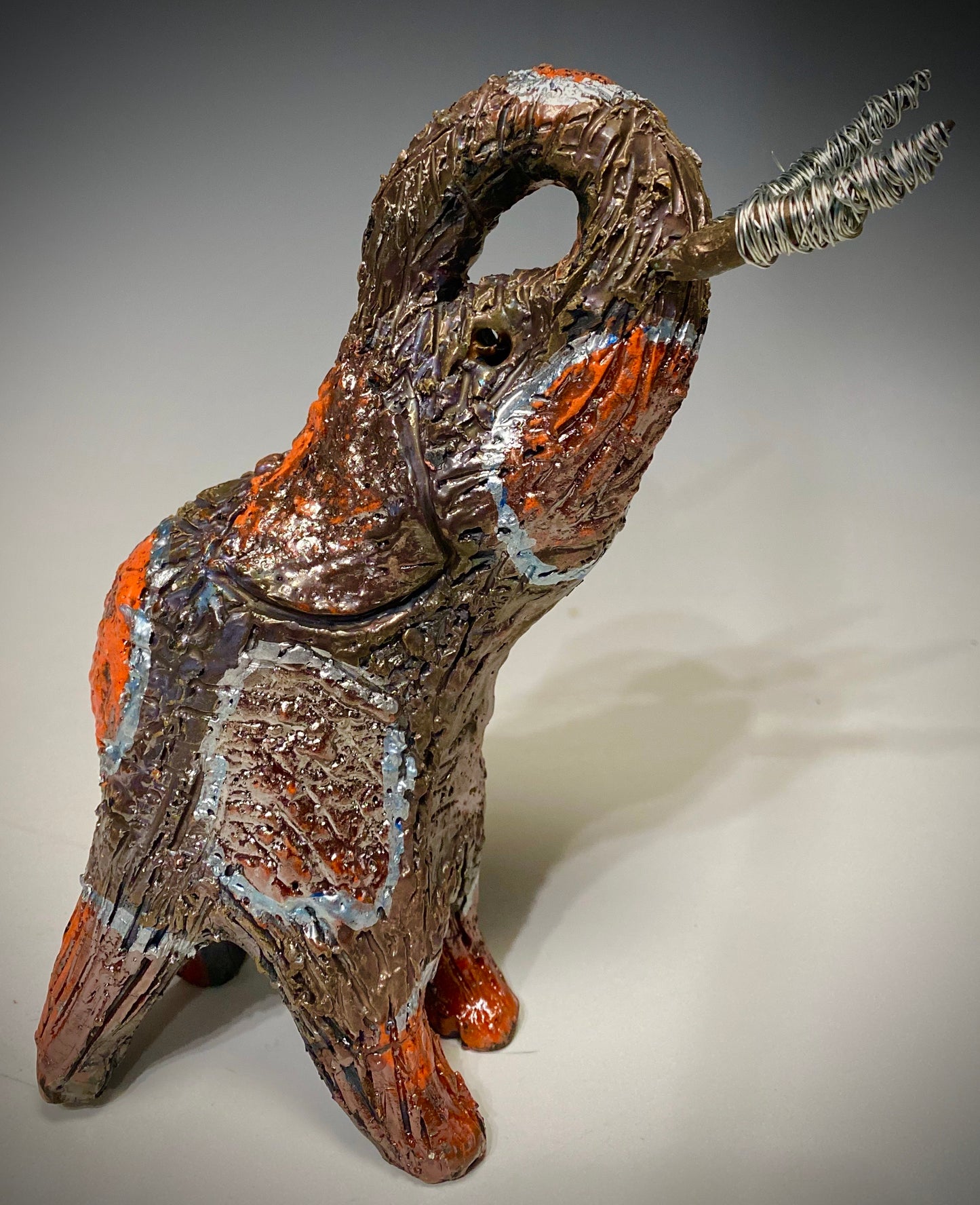 Have you HERD!!!!!! Just one of these lovely Raku Fired Elephant will make an excellent gift for your friend, sorority or for your home’ special place centerpiece. 9.5" x 4" x 7" 1.10 lbs Silver wire beaded tusk Beautiful metallic copper and orange raku colors For decorative purposely only.