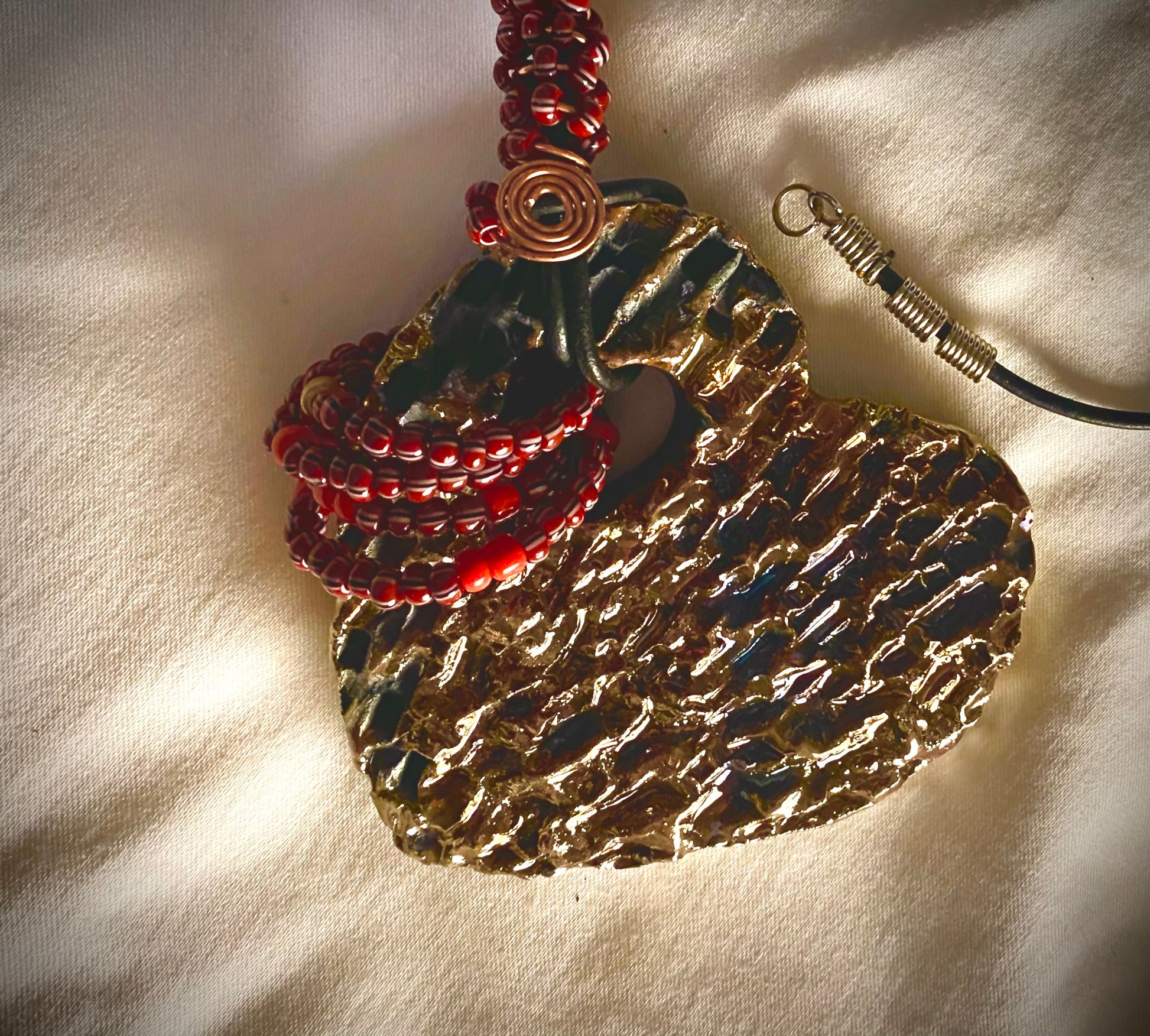 Have A Heart ! Each heart pendant is handmade with love! It is 3"x 3" and weighs approx. 3ozs. This pendant has a gold metallic raku glazes that renders a unique translucent  patina. The heart has a textured  pattern. It holds a spiral of ruby mini beads on a spiral copper wire. This pendant has a nice 12" black suede cord!
