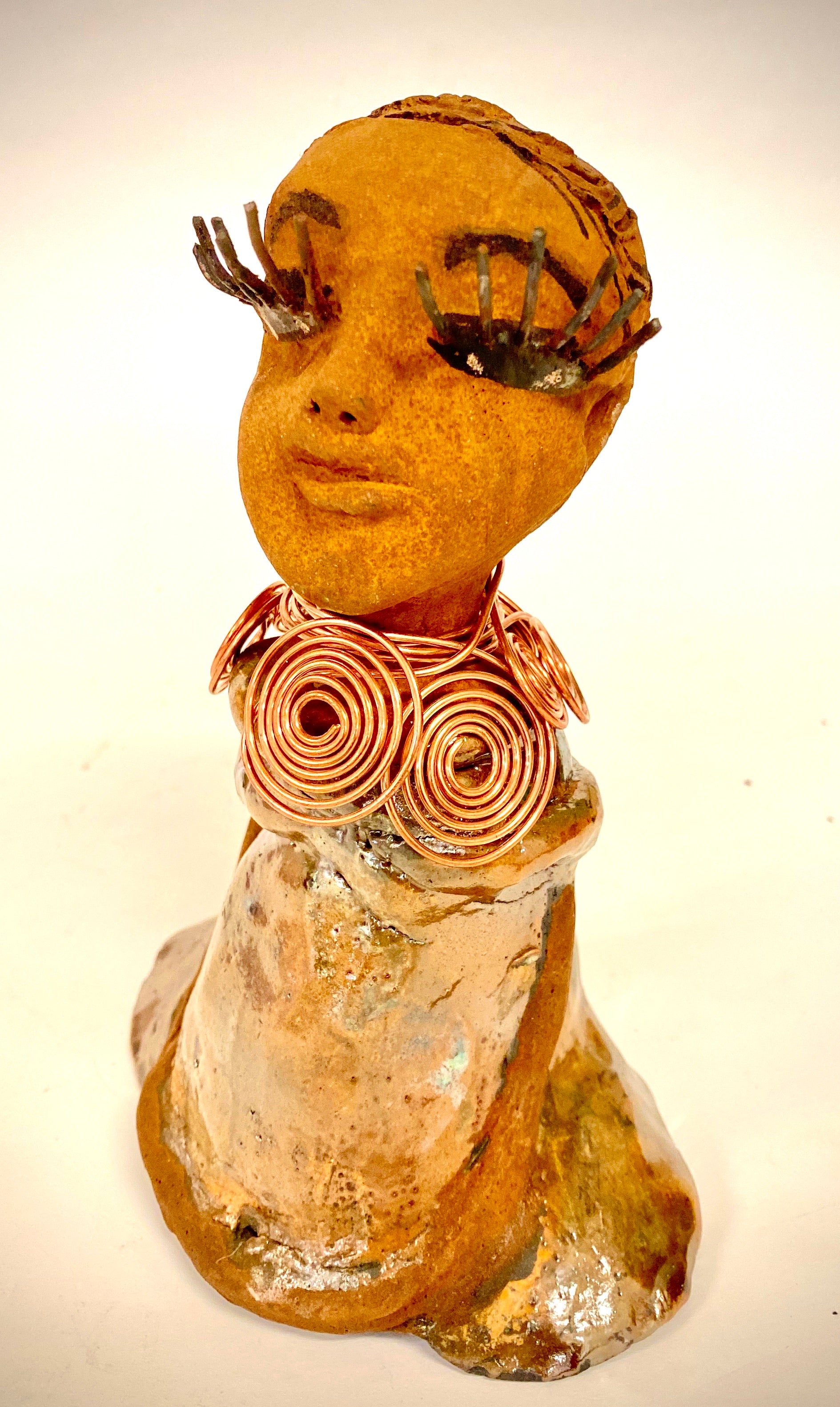Charlotte stands 7" x 5" x 4" and weighs 1.03 lbs. She has a lovely honey brown complexion with  reddish brown lips. She has a braided hairstyle.  Charlotte has a colorful metallic  yellow green antique copper glazed dress. She wears a spiral copper wire necklace. With eyes slightly opened, Charlotte has hopes of finding a new home.