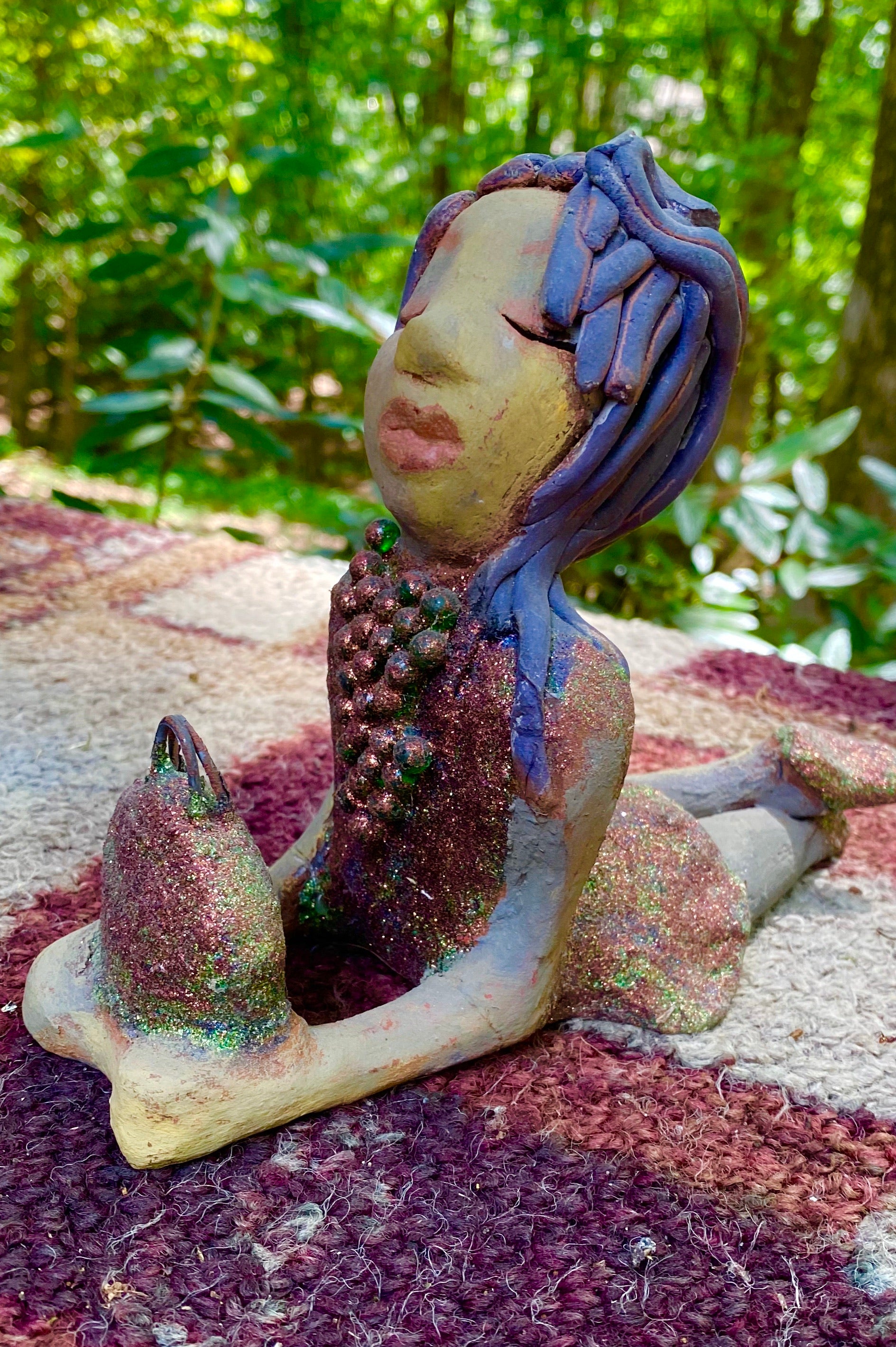 Lacey is going places but she's not leaving her bag! Lacey stands 6" x 3" x 7.5" and weighs 1.08 lbs. She has a lovely beige olive green complexions with ruby red lips. Her hair is made of coiled clay. Lacey is holding her handbag which matches her copper glittered dress.