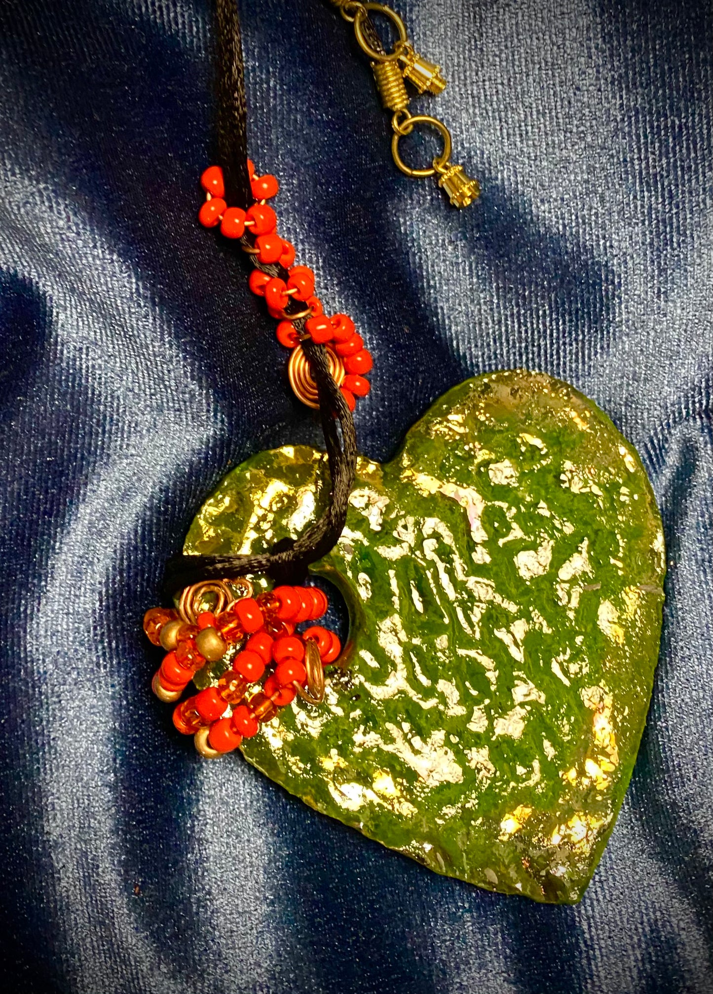Have A Heart ! Each heart pendant is handmade with love! It is 3"x 3" and weighs approx. 3ozs. This pendant has a green metallic raku glazes that renders a unique translucent patina. The heart has a textured pattern . It holds a spiral of green mini beads on a spiral copper wire. This pendant has a nice 12" black suede cord!