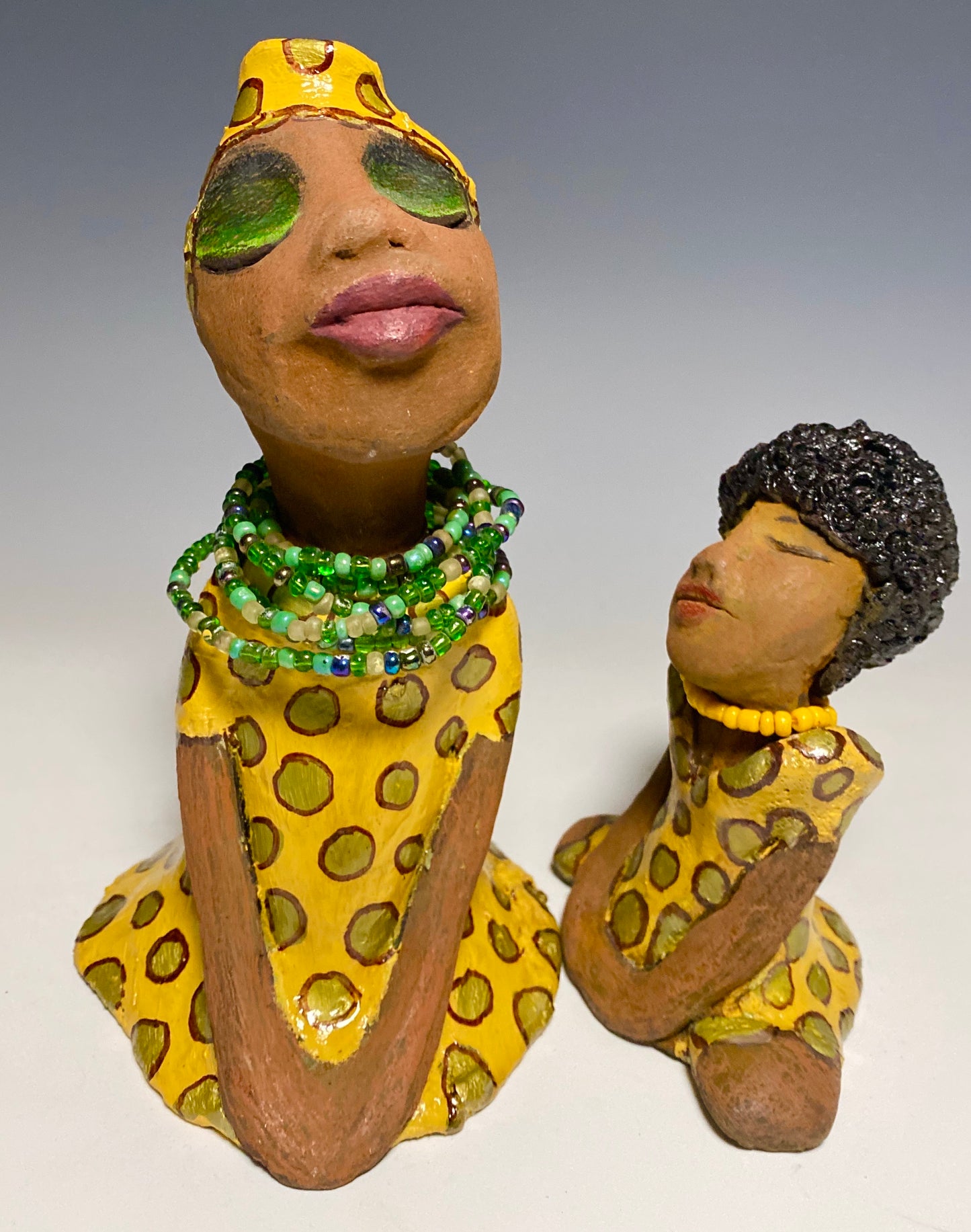 Meet Sharon! Sharon stands" 8 x 5" x 5" and weighs 1.5 lbs She wears a cute spotted autumn yellow dress with matching hat and emerald green beads. Her long loving arms rest at her side. Check out Sharon's little sister named Shelia! With the current situation we All are going through, Shelia will place a smile on your face during this challenging time.