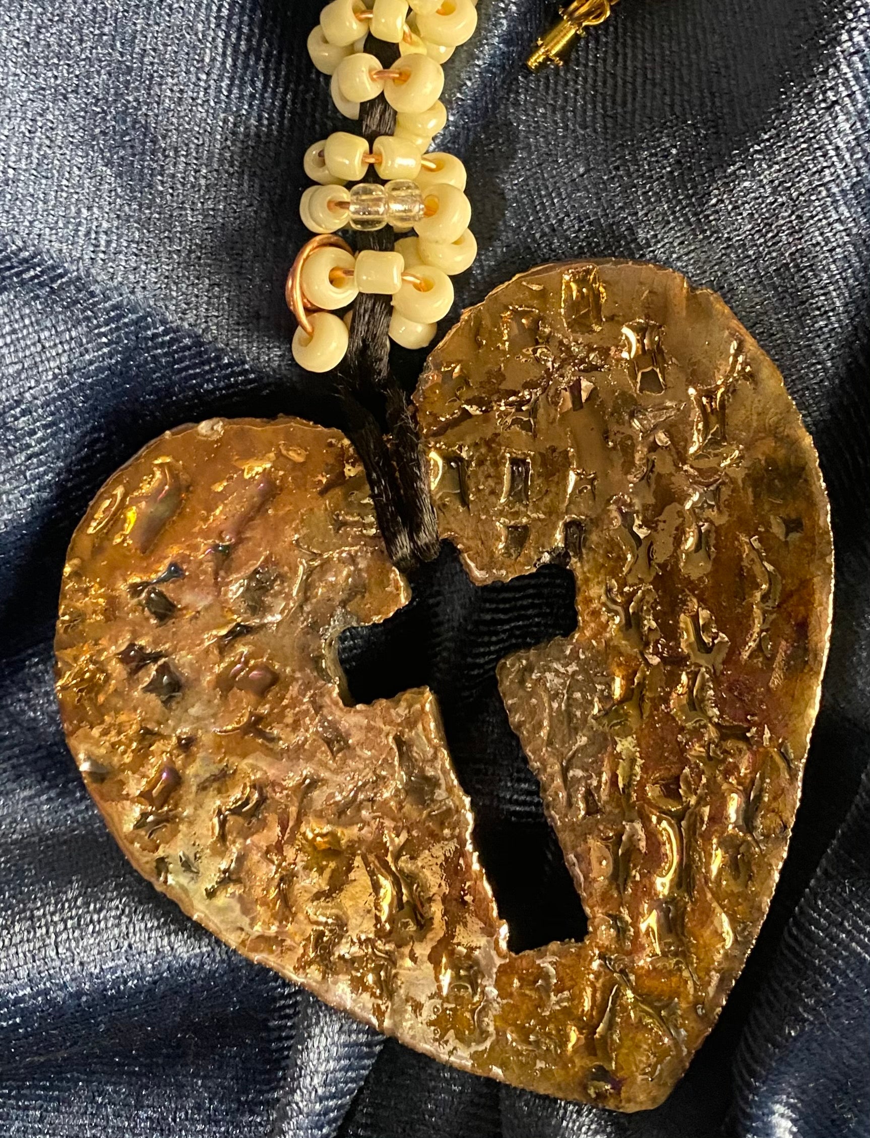 Have A Heart ! Each heart pendant is handmade with love! It is 3"x 3" and weighs approx. 3ozs. This pendant has an off white and gold metallic raku glazes that renders a unique translucent  patina. The heart  has a textured  pattern with a cut out cross in the center.. It holds a spiral of off white mini beads on a spiral copper wire. This pendant has a nice 12" black suede cord!