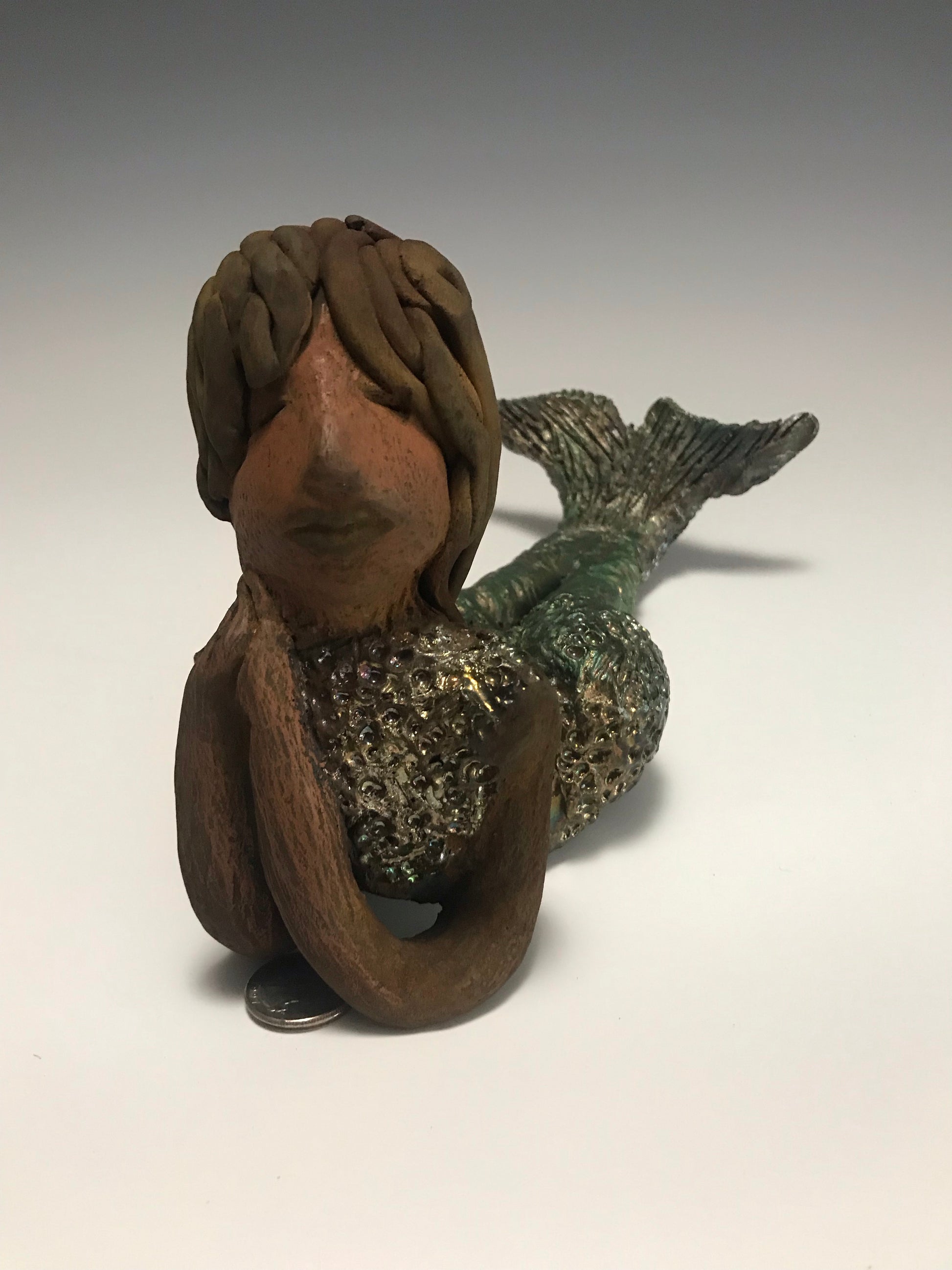 Meet Belinda!  Belinda is a voluptuous mermaid. She stands 6.5" X 5" 9.5" and weighs 2.04 lbs. Belinda has a dark chocolate complexion.      She wears a  dark smokey clay hairstyle.      She wears a glossy metallic swimsuit.     Belinda has a wide tail.     She will  definitely get somebody's attention.   Let Belinda get the conversation started at your home!