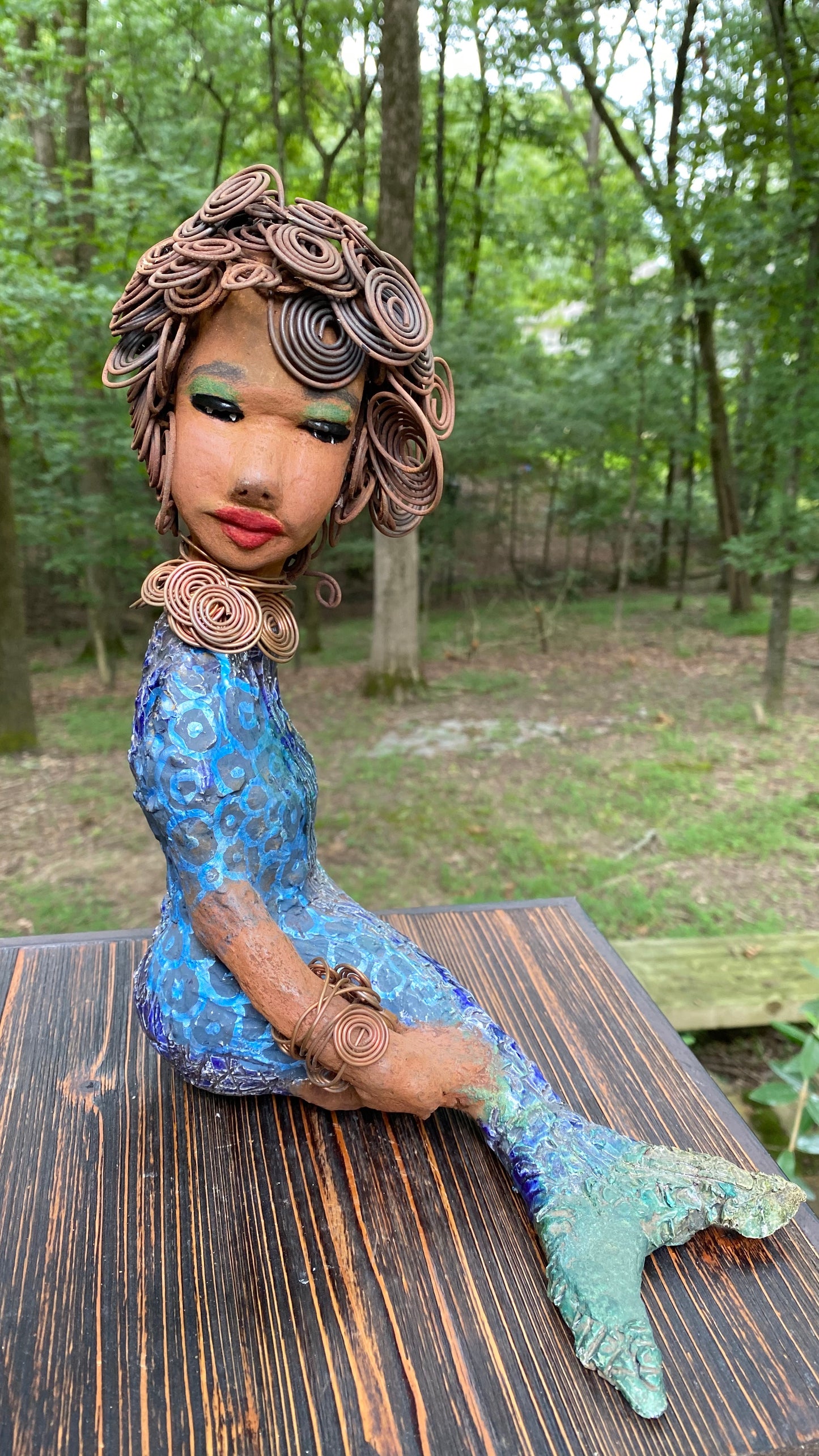 Meet Shelia E.! She is such a Lady I mean Mermaid! Shelia stands 12" x 10" x 4" and weighs 3.13 lbs. Shelia has a two tone honey brown complexion. She has over 15 feet of spiral wire hair which took over two hours to style. Shelia wears a textured sky blue swimsuit Her layered spiral copper necklace hangs above her long loving arm. Shelia is such a ladylike Mermaid. She sits tall and proud. Compare her to Harmony the mermaid. Give Shelia or Harmony a special place to sit in your home!